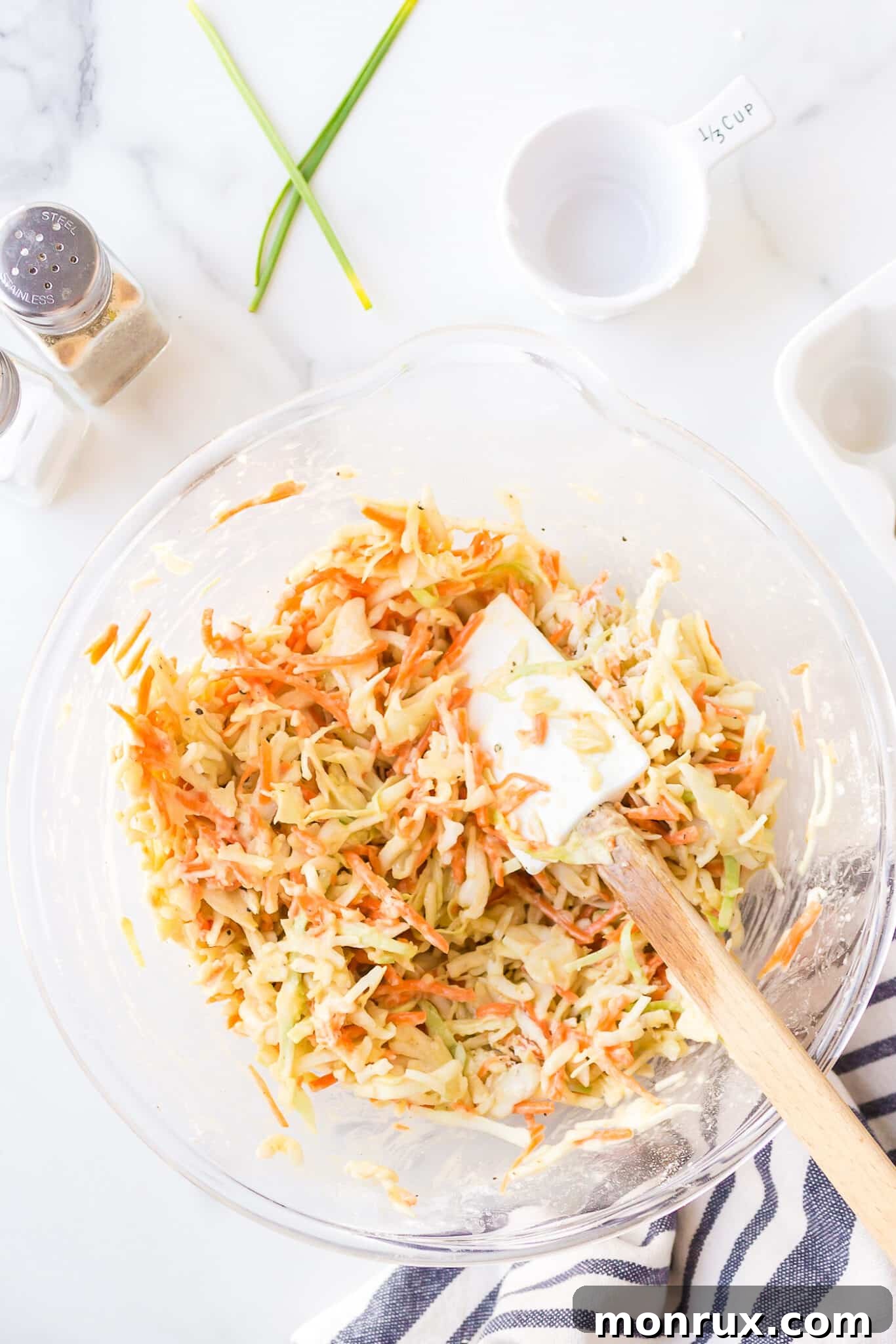 A spatula diligently stirring the cabbage fritter mixture in a bowl, ensuring all ingredients are thoroughly combined and evenly distributed.