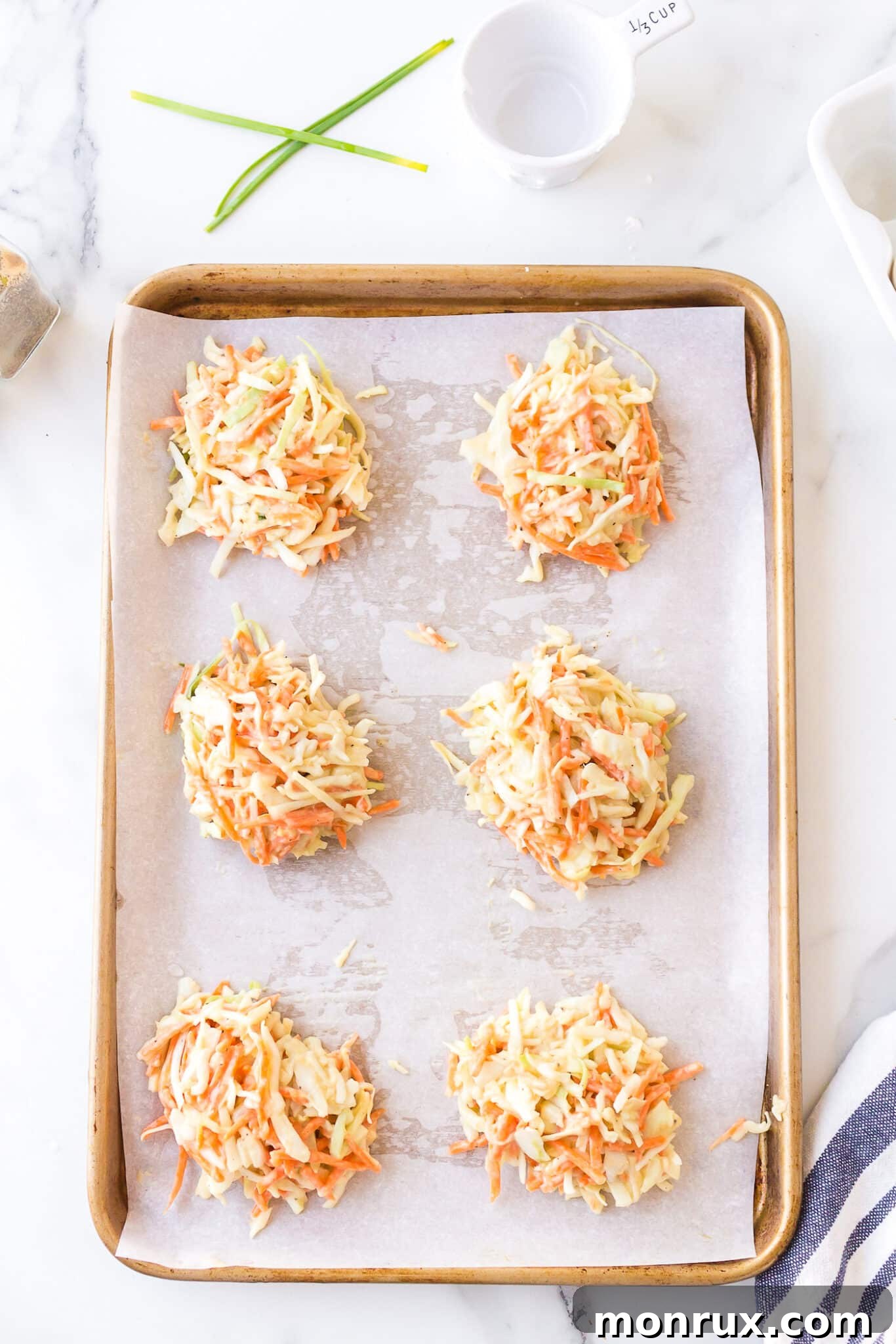 Neatly formed, round cabbage fritters arranged on a parchment-lined baking sheet, ready for baking.