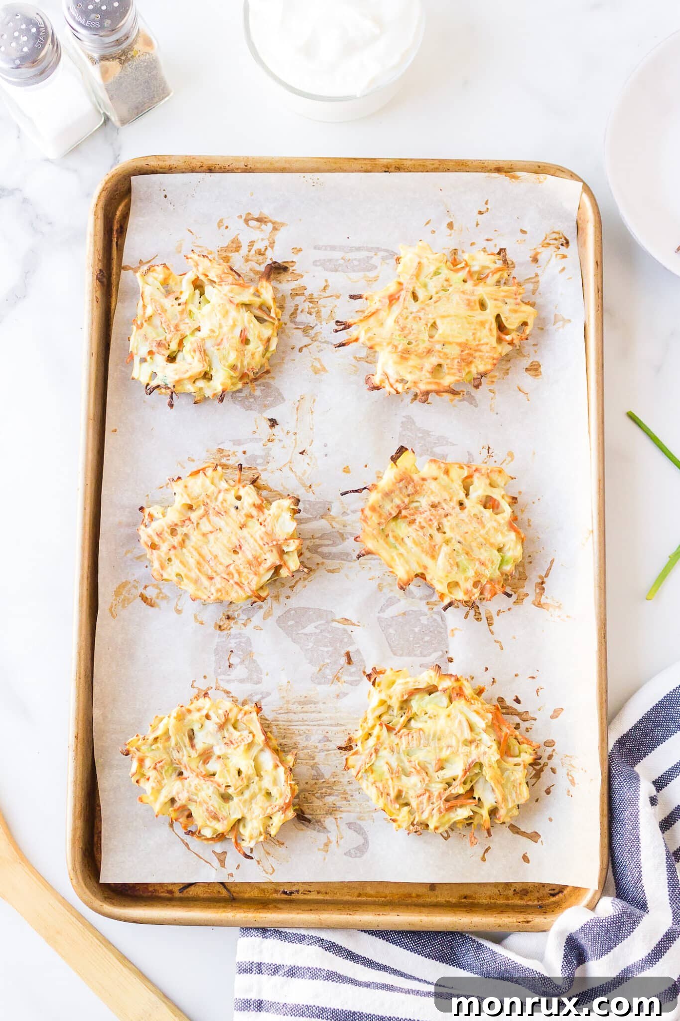 Freshly baked, golden-brown cabbage fritters arranged on a baking sheet, steam gently rising, indicating they are hot and ready to be served.