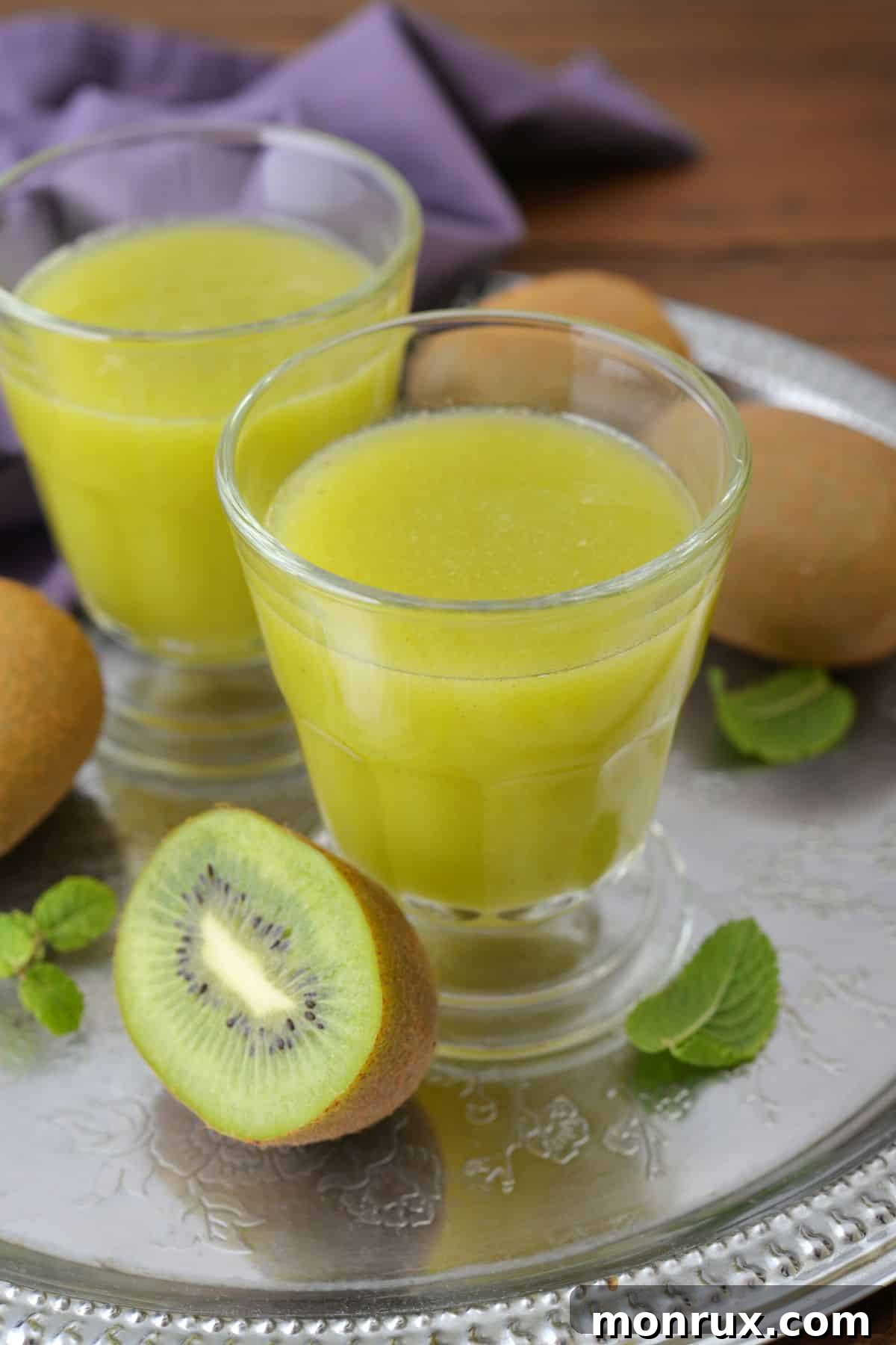 Two short glasses of freshly squeezed kiwi juice, garnished with kiwi slices.