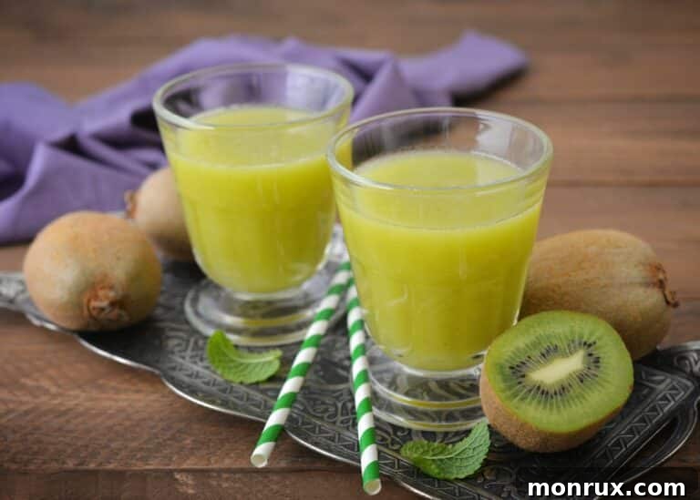 Two short glasses of freshly squeezed kiwi juice, garnished with kiwi slices.