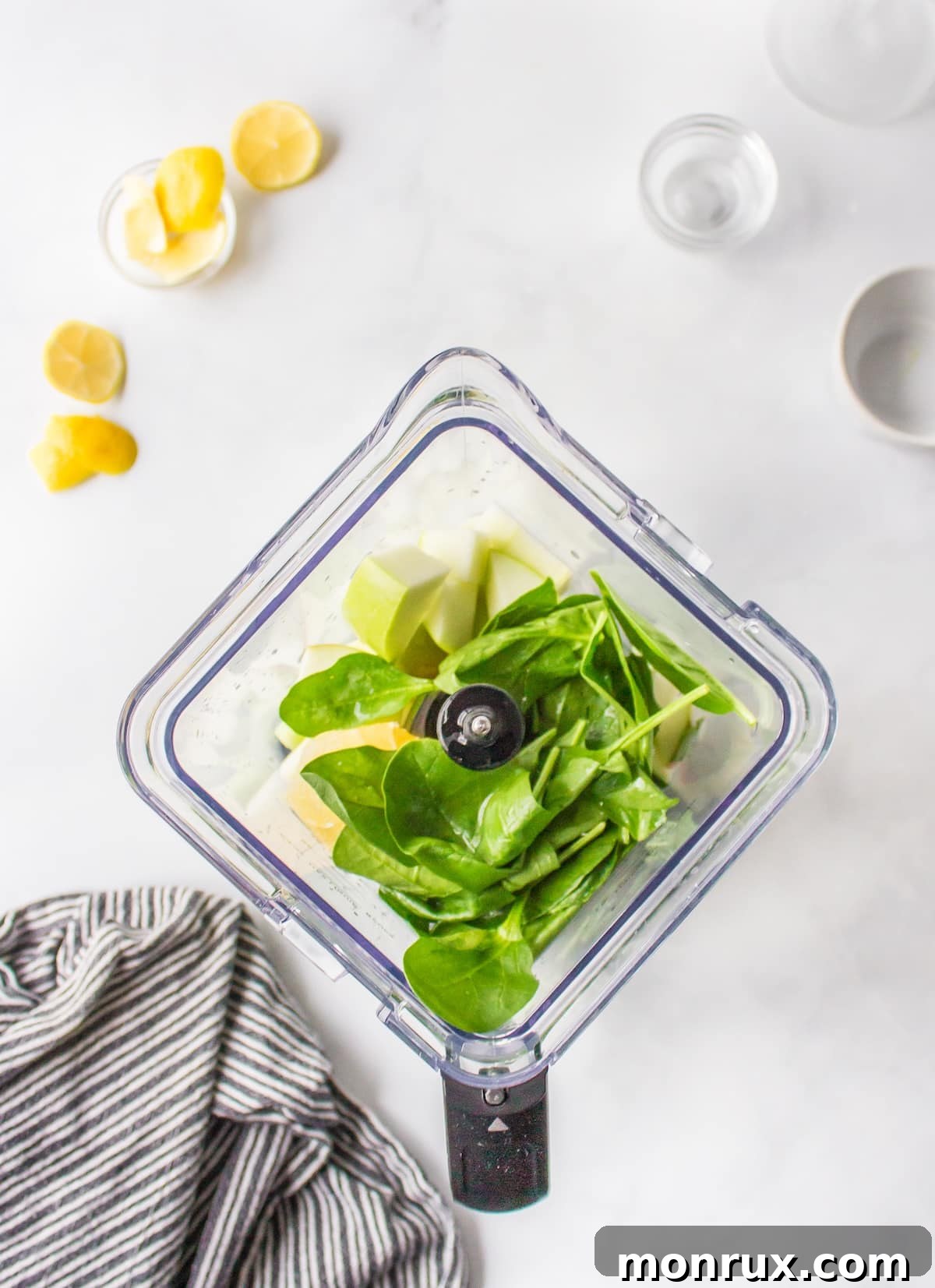 Fresh spinach juice ingredients, including spinach, celery, cucumber, green apple, and lemon, ready to be blended in a high-speed blender.