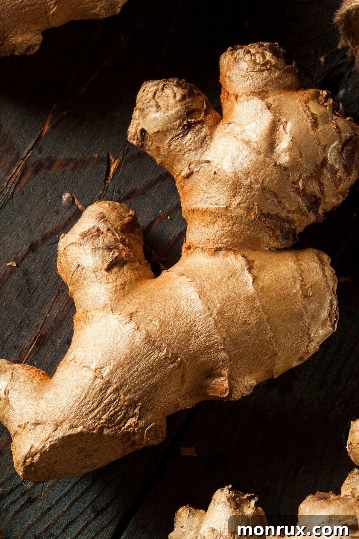 Peeled and unpeeled fresh ginger root on a cutting board, ready for use.