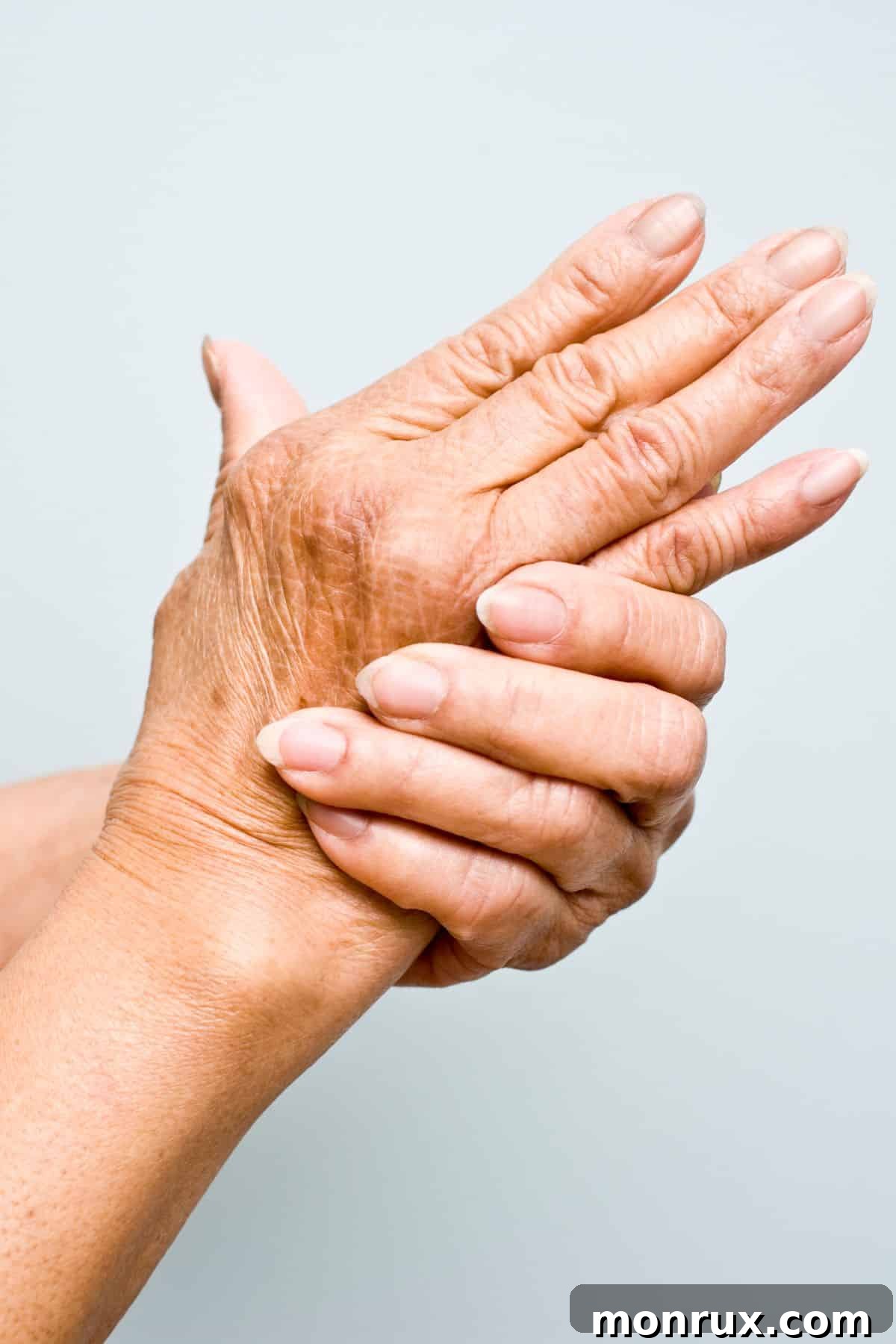 A woman gently holding her aching hand, illustrating the discomfort of arthritis.