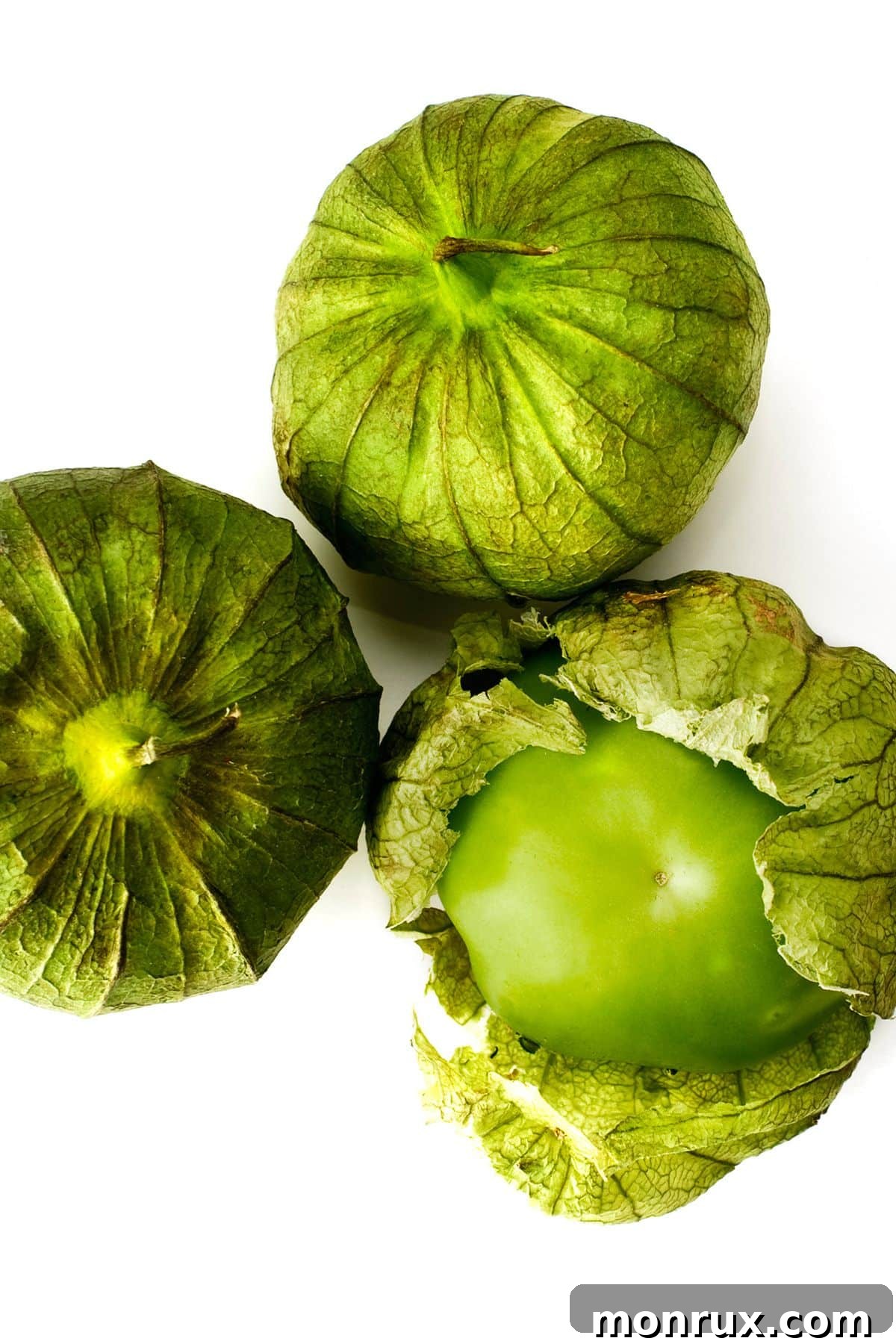 Several fresh tomatillos, still in their papery husks, arranged on a white background.