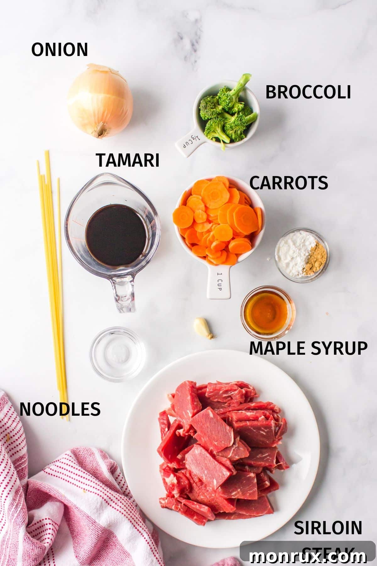Fresh ingredients laid out on a white surface, ready for making teriyaki beef noodle bowls.