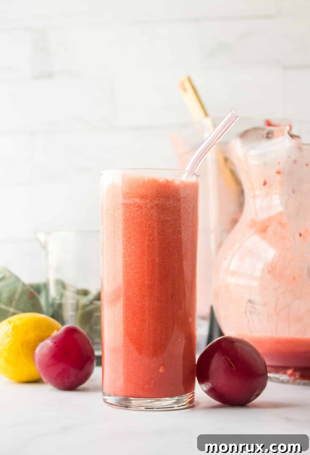 A glass of homemade plum juice with fresh plums nearby.