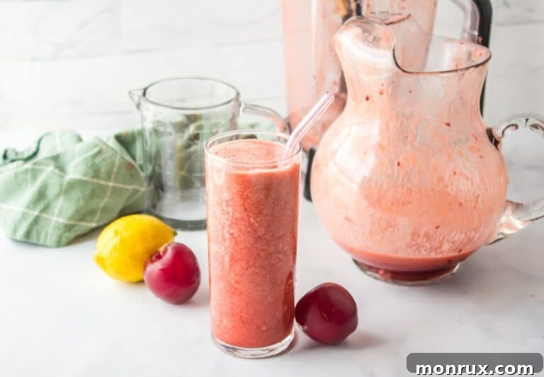 Plum juice in a glass pitcher, with a glass ready to serve.