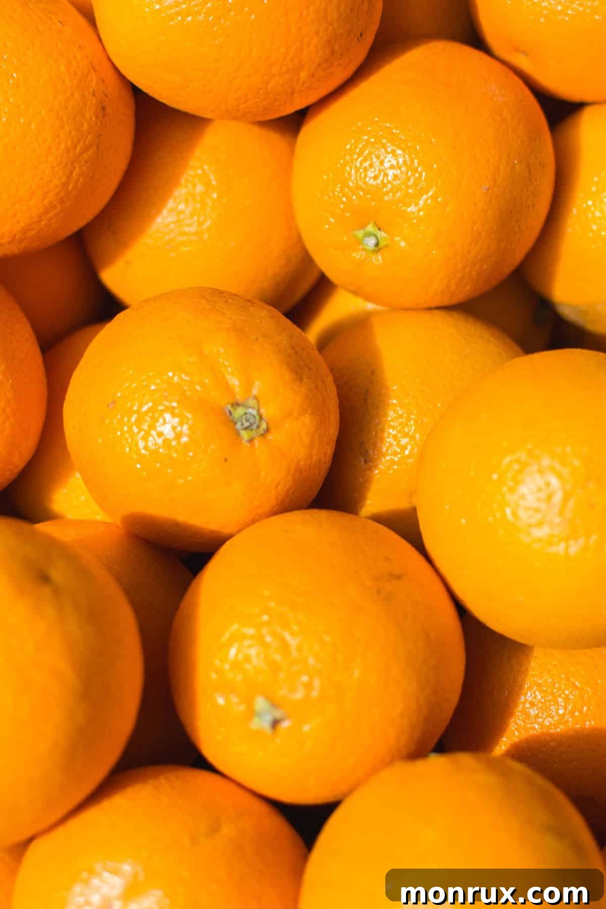 Fresh, ripe oranges covering a surface, ready for juicing.