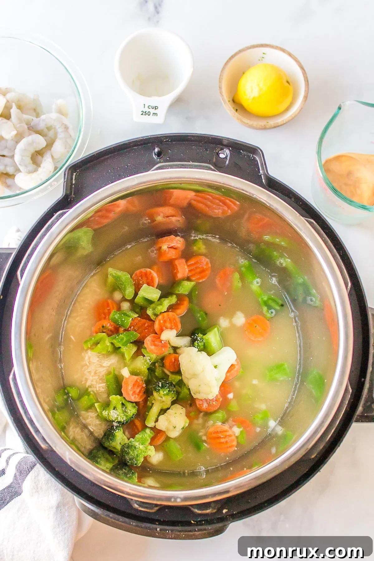 Rinsed rice, frozen veggies, and broth in the Instant Pot liner.