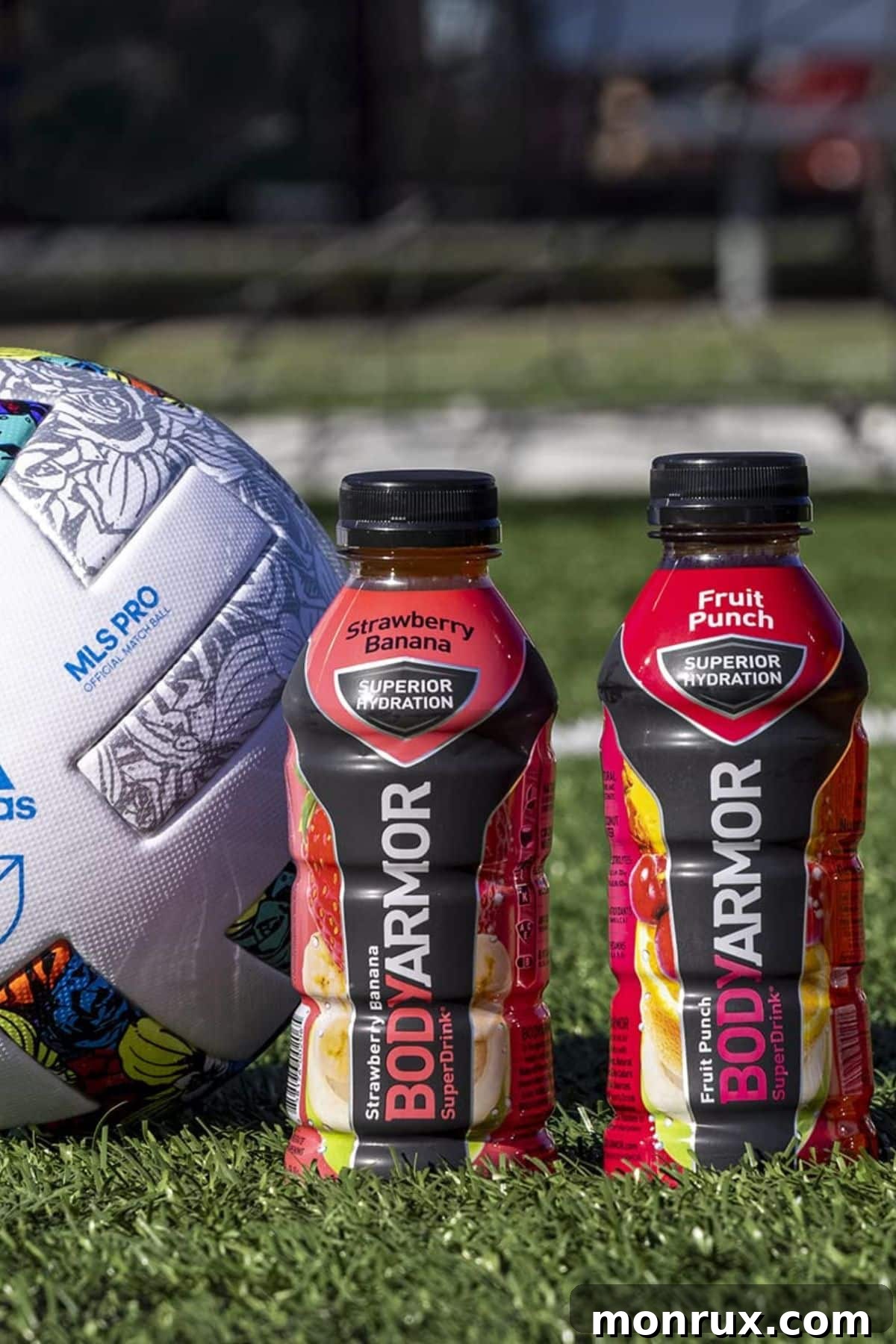 Two bottles of Body Armor next to a volleyball, illustrating an active lifestyle.