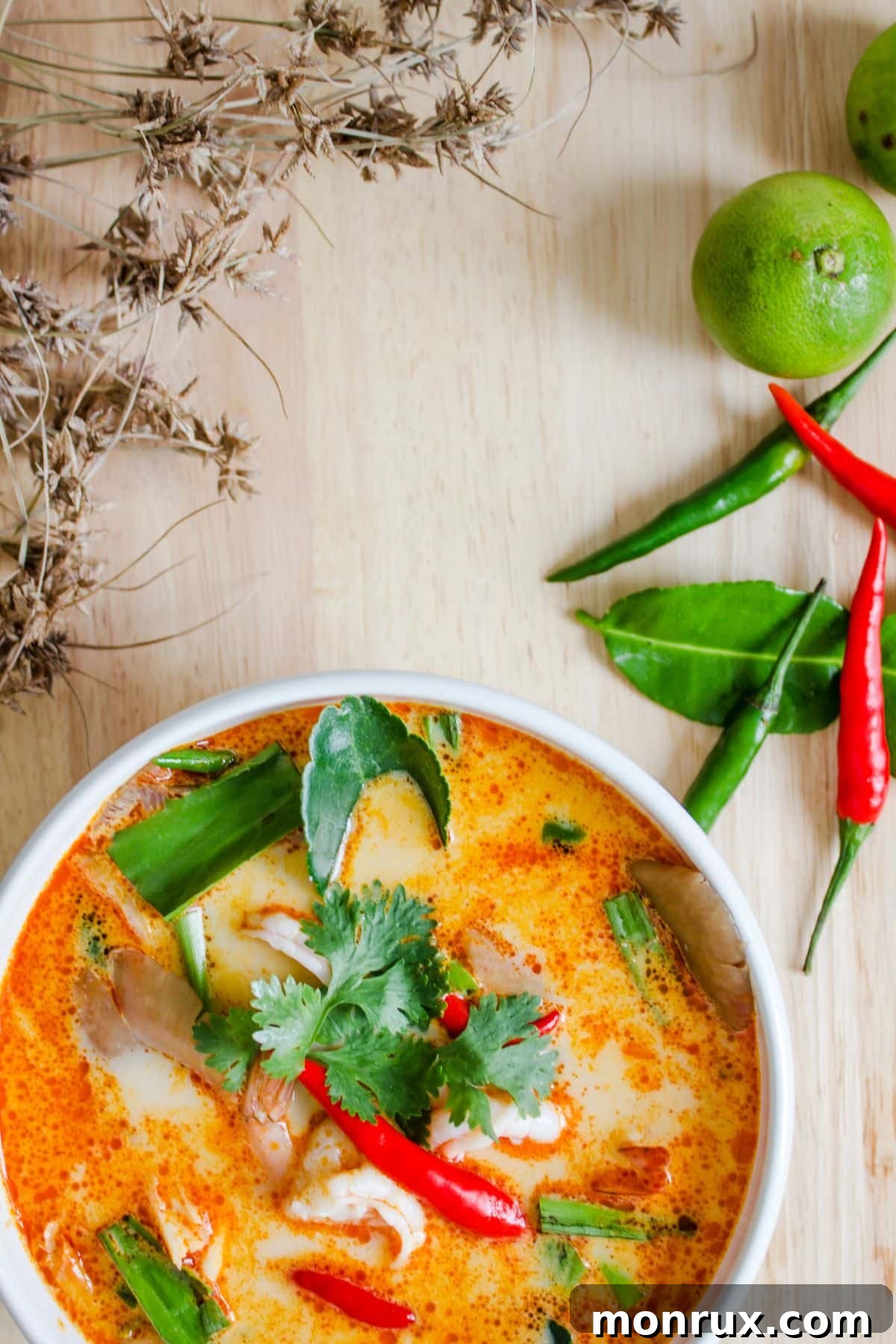A vibrant bowl of Tom Yum Goong, a spicy Thai soup with shrimp and herbs.