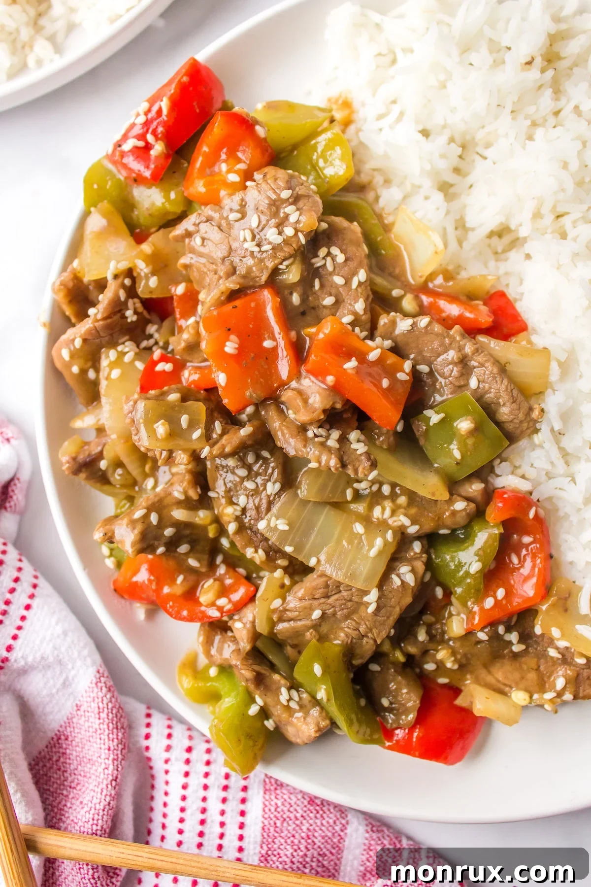 copycat P.F. Chang's Pepper Steak on a white plate with rice, garnished with sesame seeds.
