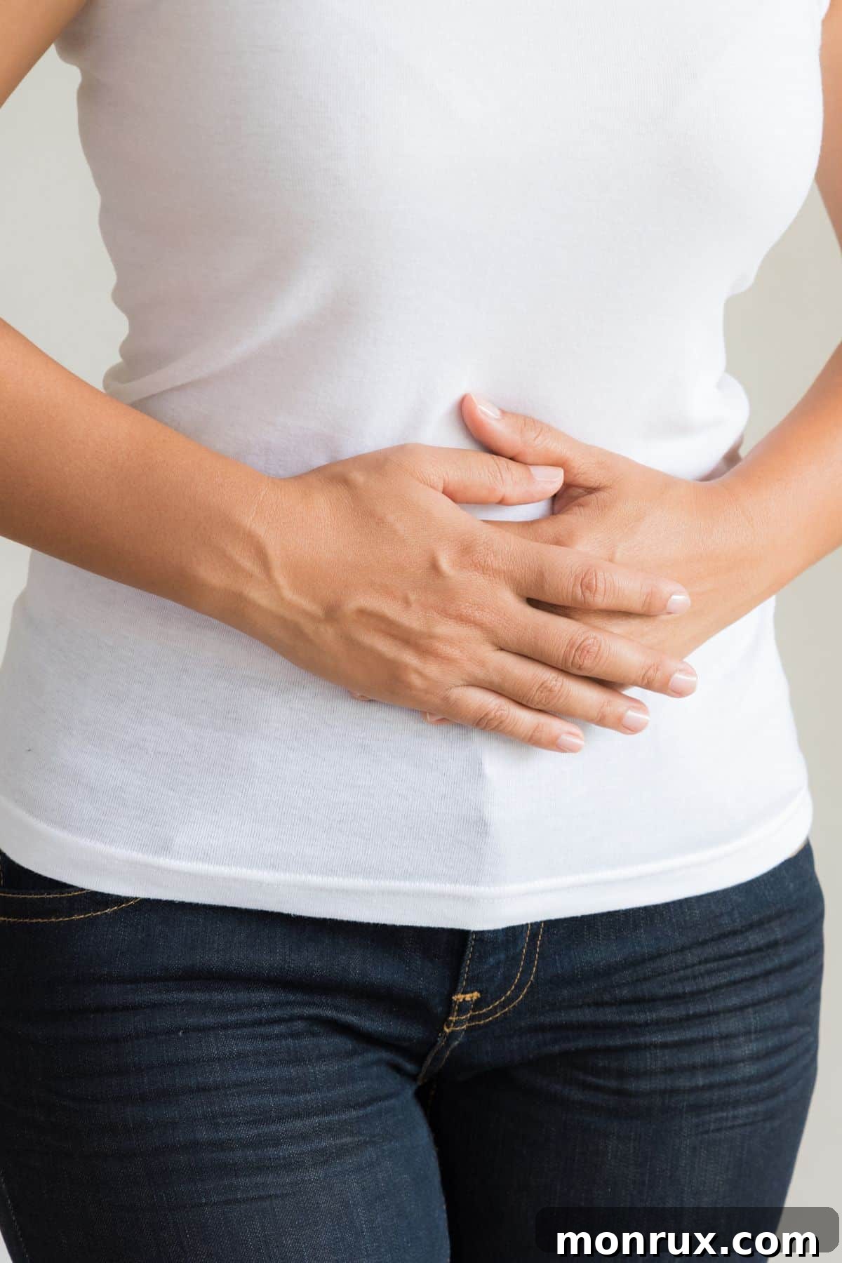 A woman holds her abdomen, indicating bloating and discomfort.