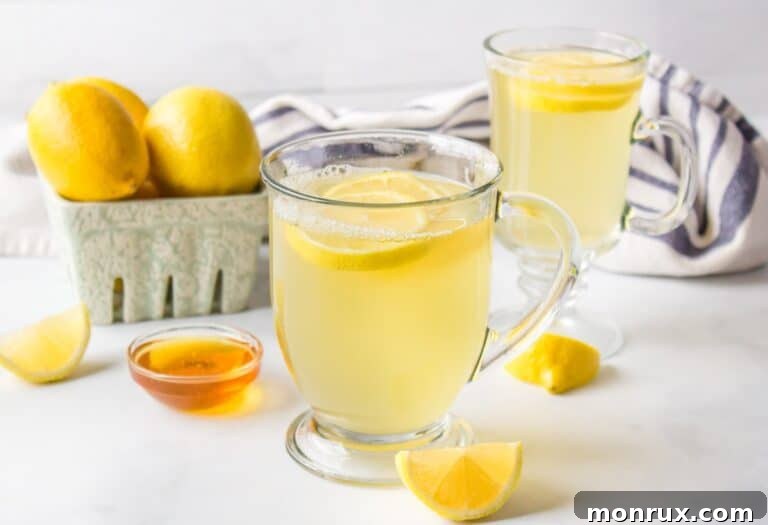 Two mugs of honey lemon tea on table.