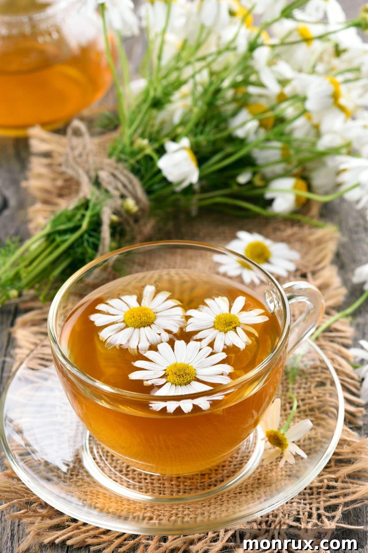 A cup of chamomile tea on a table, garnished with chamomile flowers.