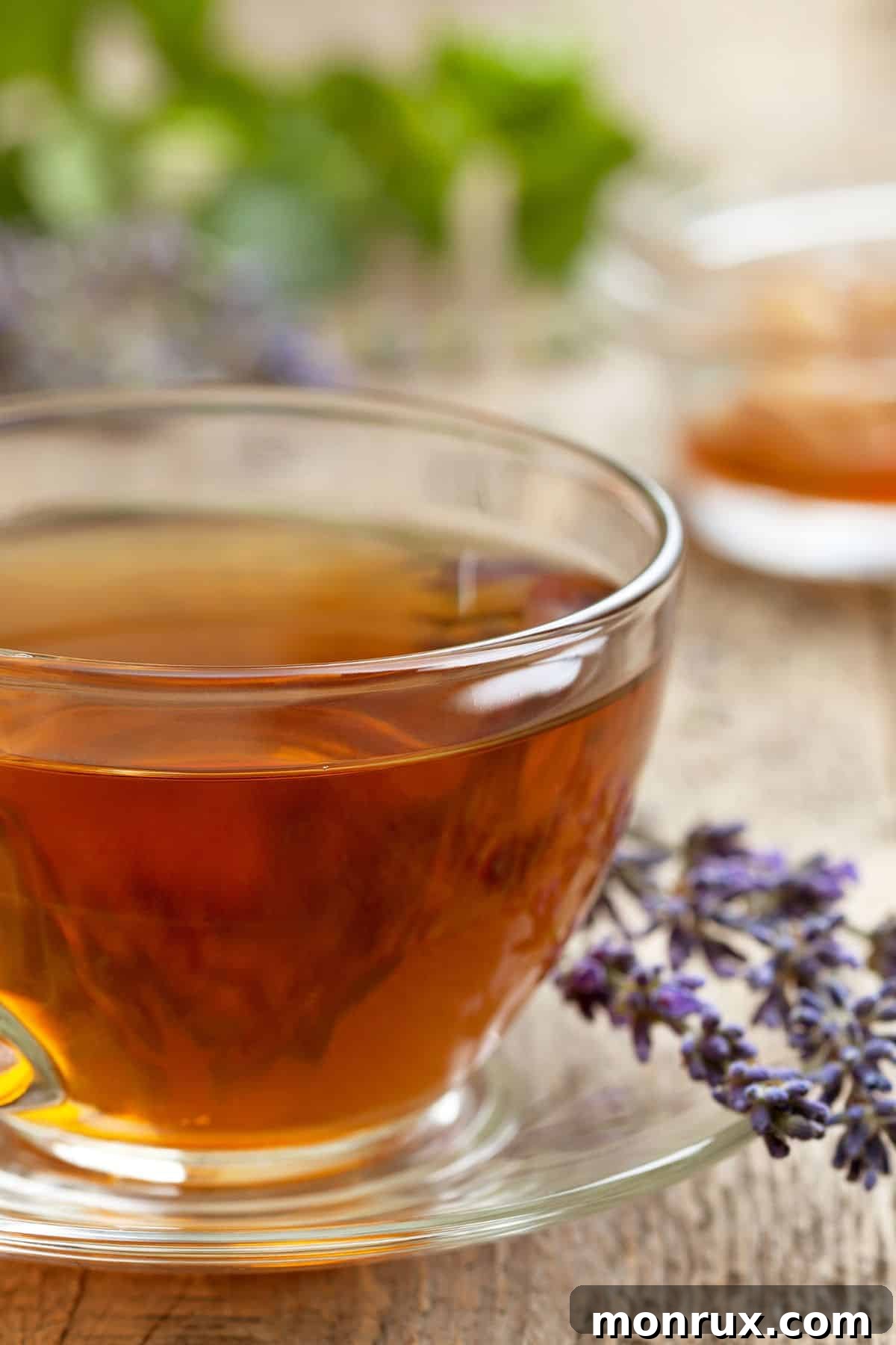A clear mug of lavender tea with lavender flowers.
