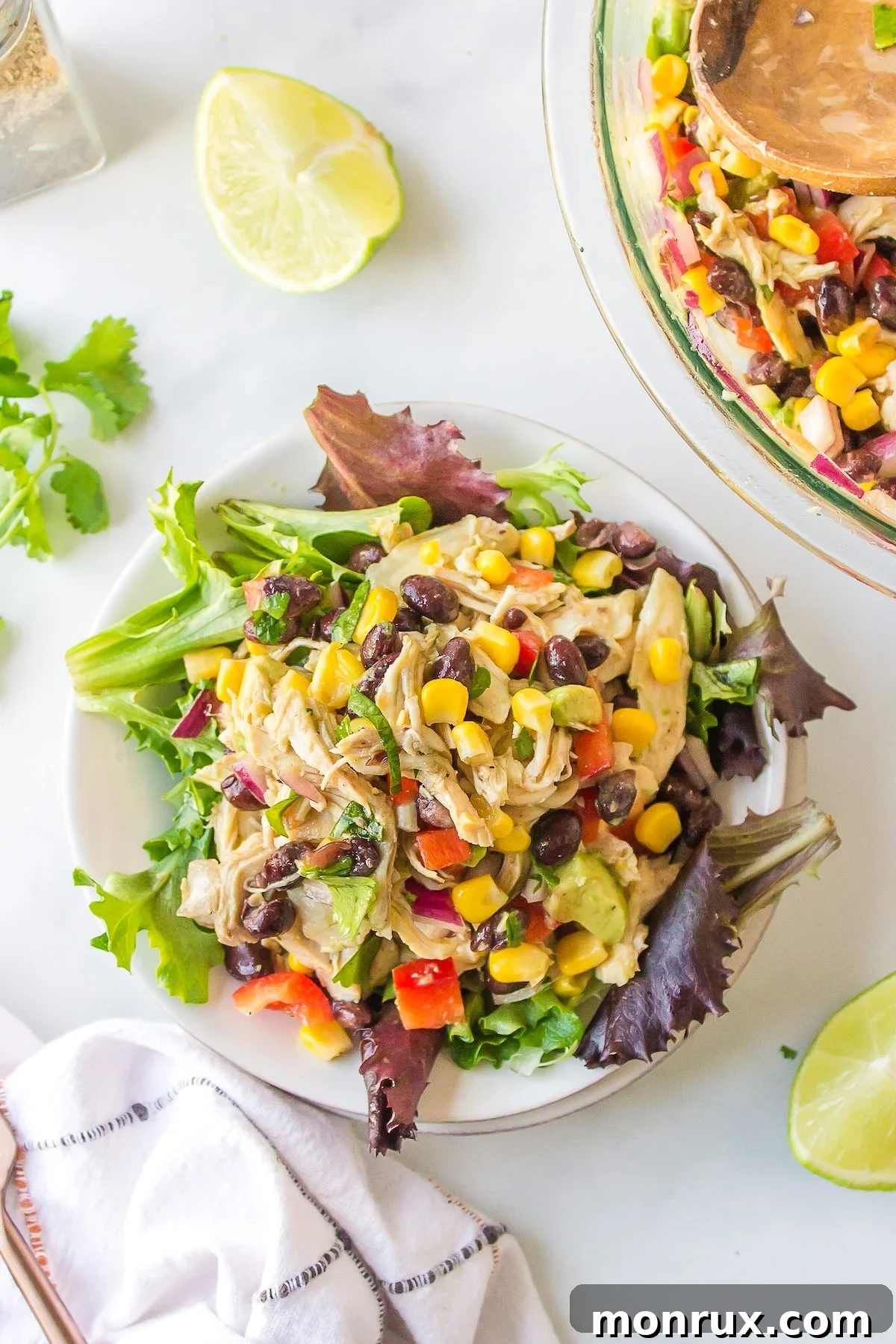 A vibrant bowl of Southwest Chicken Salad served over crisp romaine lettuce, featuring shredded chicken, black beans, corn, and avocado.