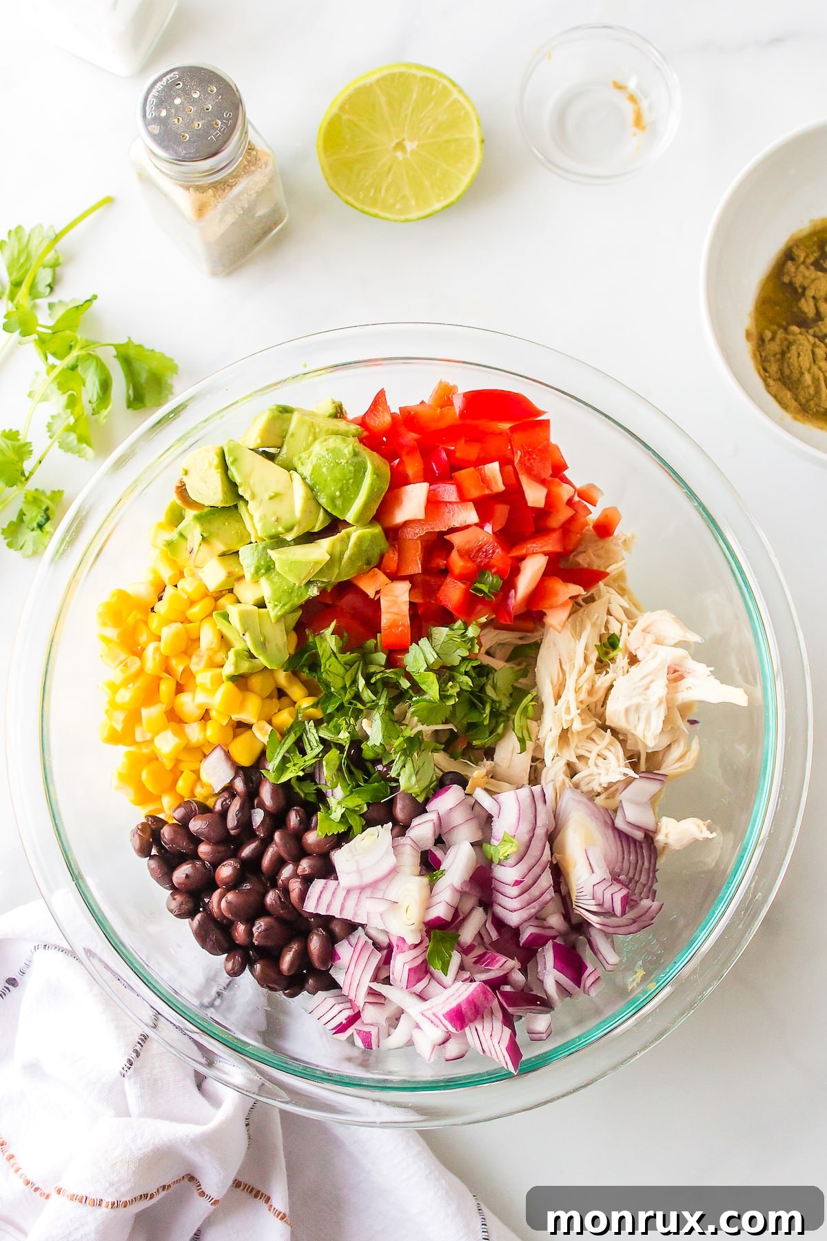 A large clear bowl filled with the colorful ingredients of Southwest Chicken Salad, before being tossed with dressing.