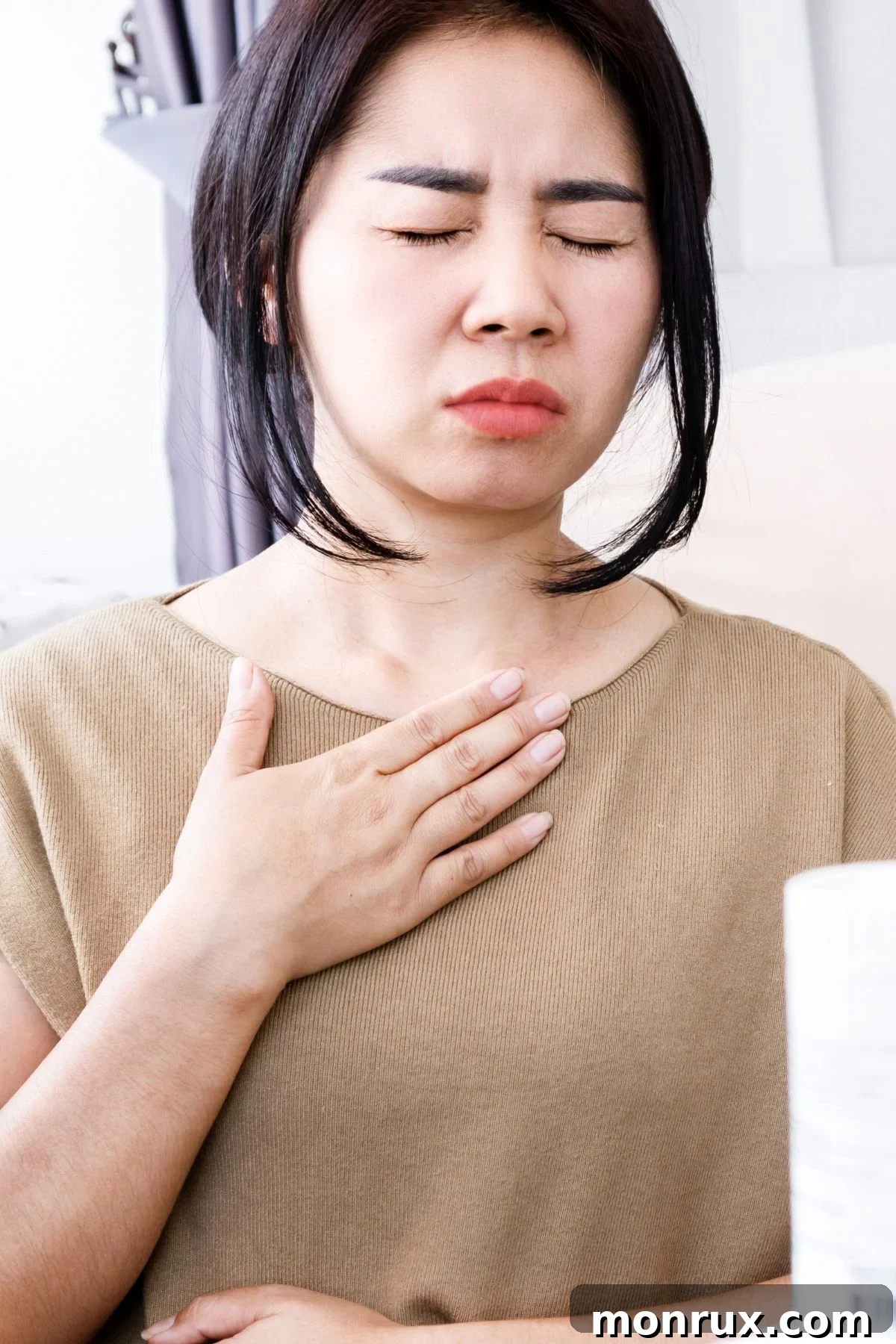 A woman touching her neck with her eyes closed, illustrating discomfort or awareness of swallowing.