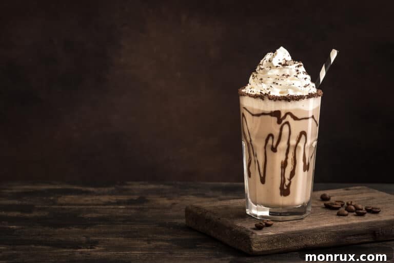 A dairy-free iced mocha topped with whipped cream in a glass with chocolate syrup, ready to be served.