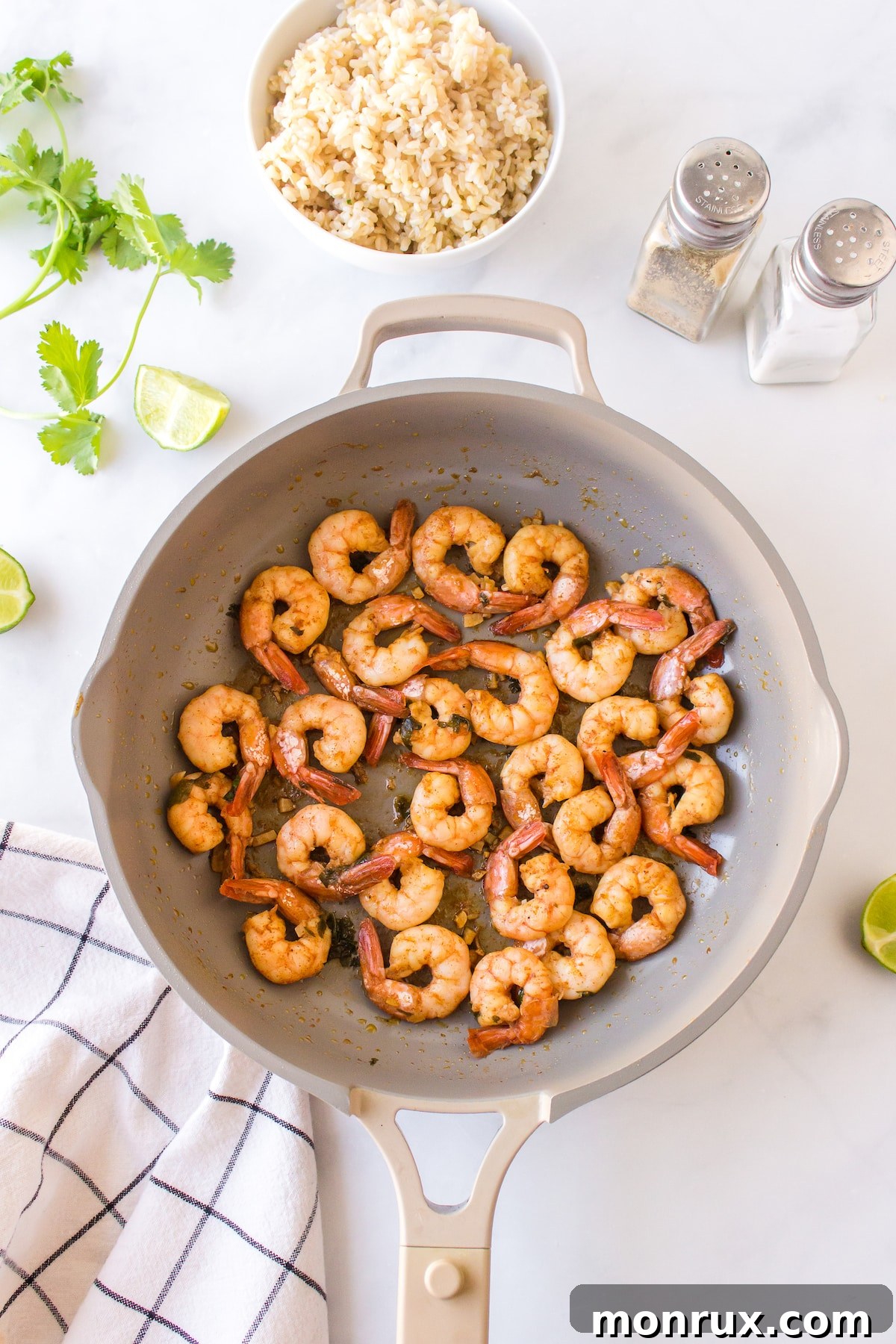 A close-up of shrimp being flipped in a skillet to cook the other side, showcasing their changing color.