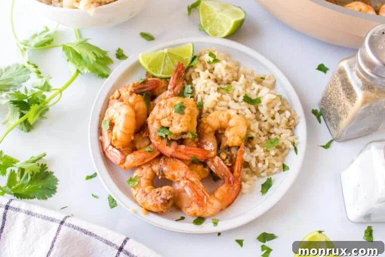 A vibrant plate of homemade Costco copycat cilantro lime shrimp, served alongside fluffy white rice, garnished with fresh cilantro and lime wedges.