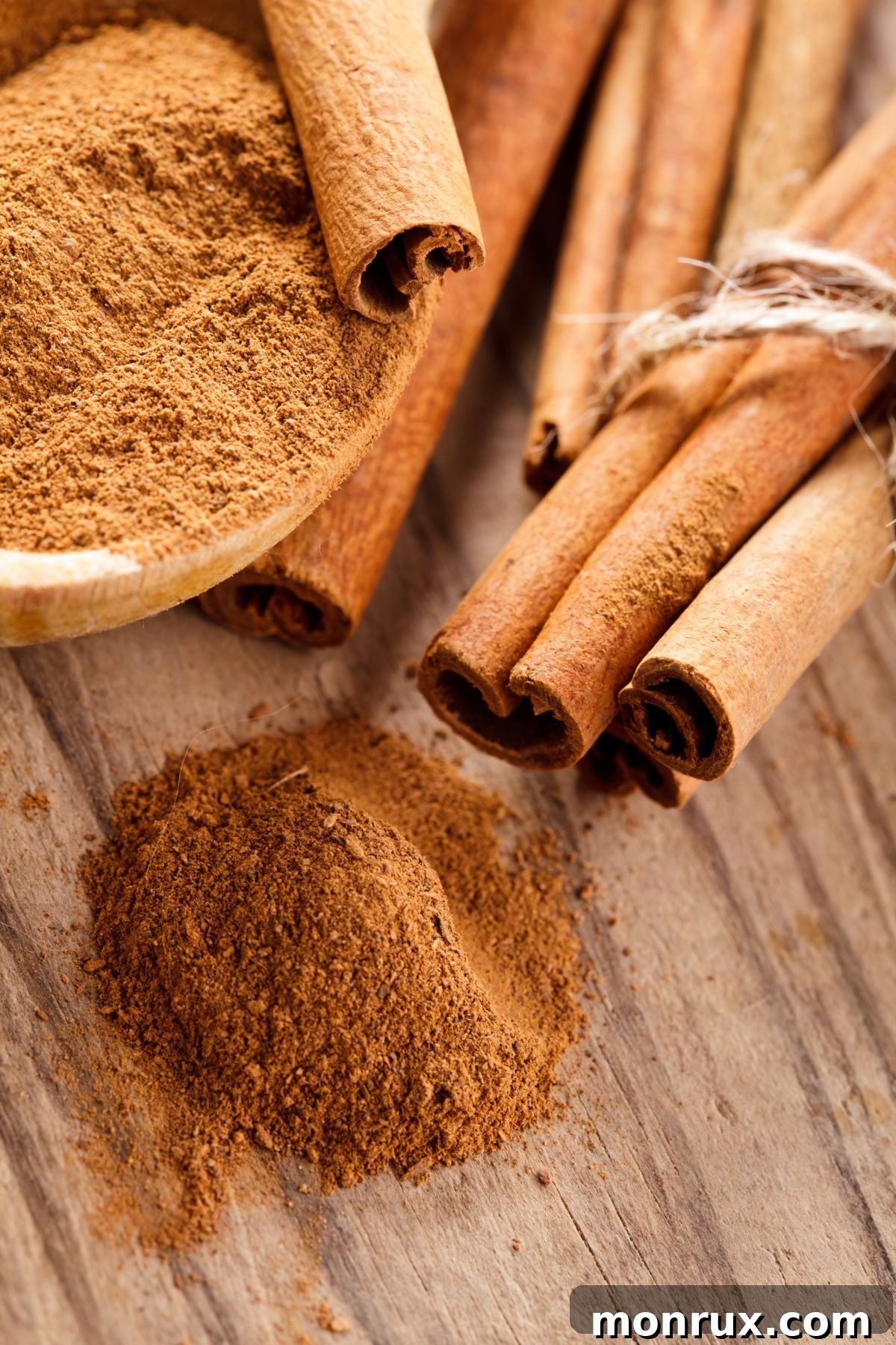 A wooden bowl filled with ground cinnamon, with some spice elegantly spilling out, highlighting its aromatic presence.