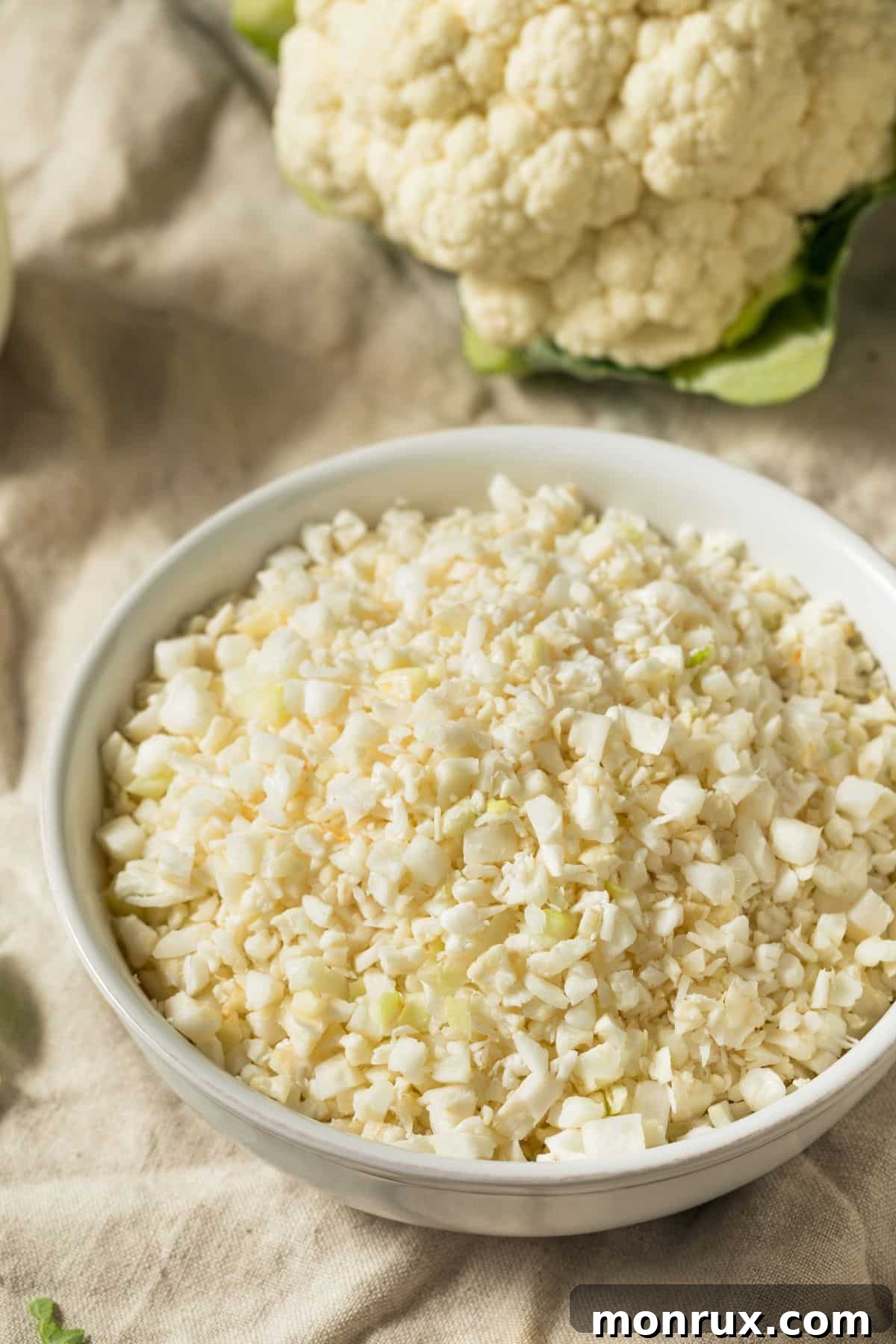 A rustic wooden bowl filled with fluffy, white riced cauliflower, emphasizing its versatility as a healthy ingredient.