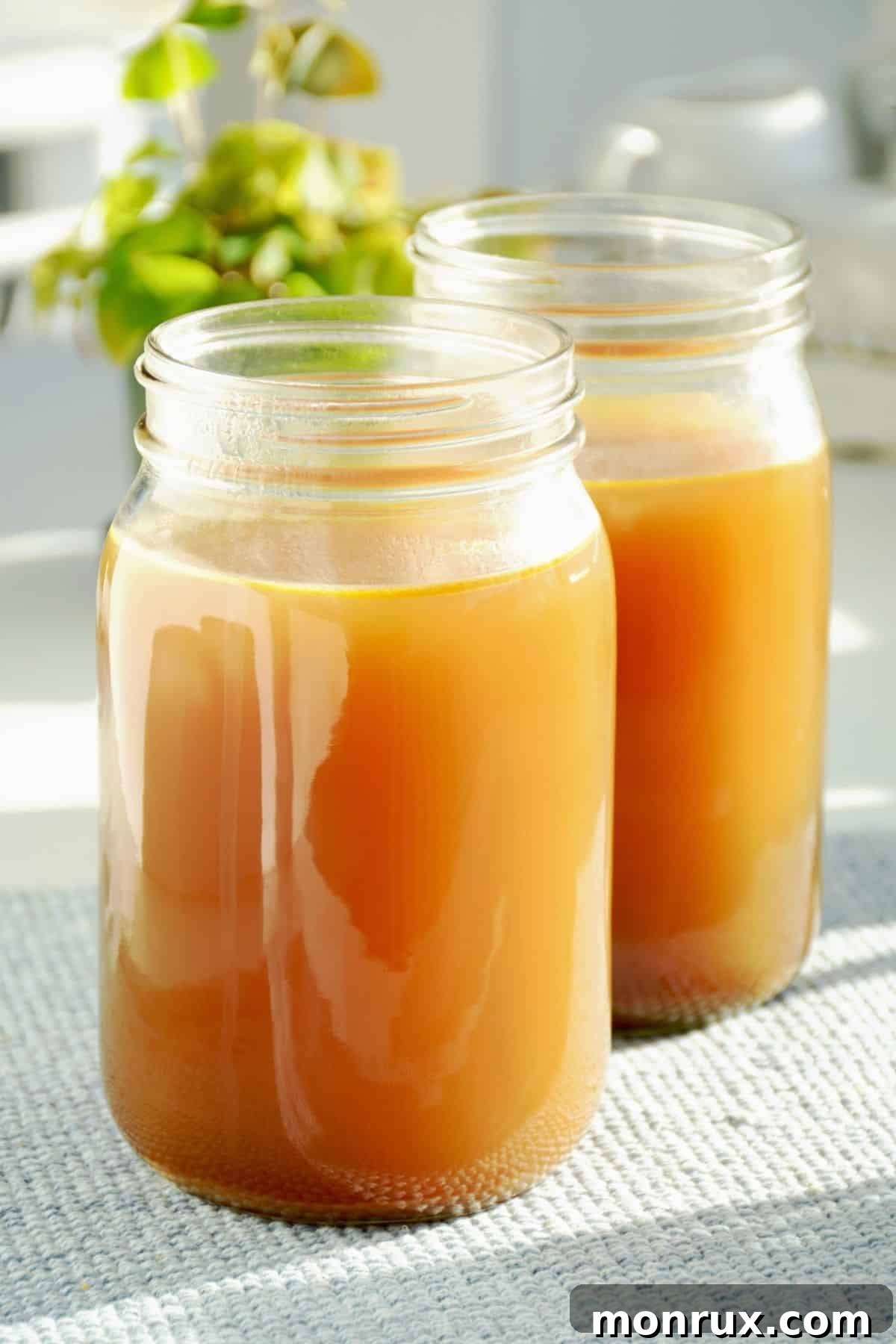 Two clear quart jars filled with golden, rich homemade bone broth, showcasing the quality liquid that forms the base of this recipe.