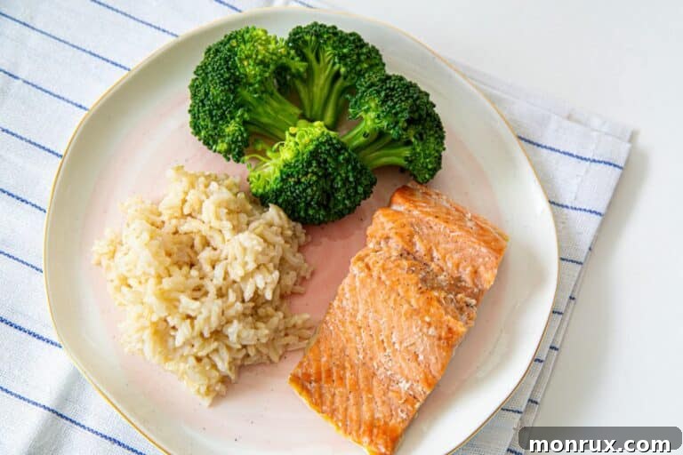 A close-up shot of fluffy bone broth rice on a plate with healthy green vegetables and a piece of protein, highlighting a balanced meal.