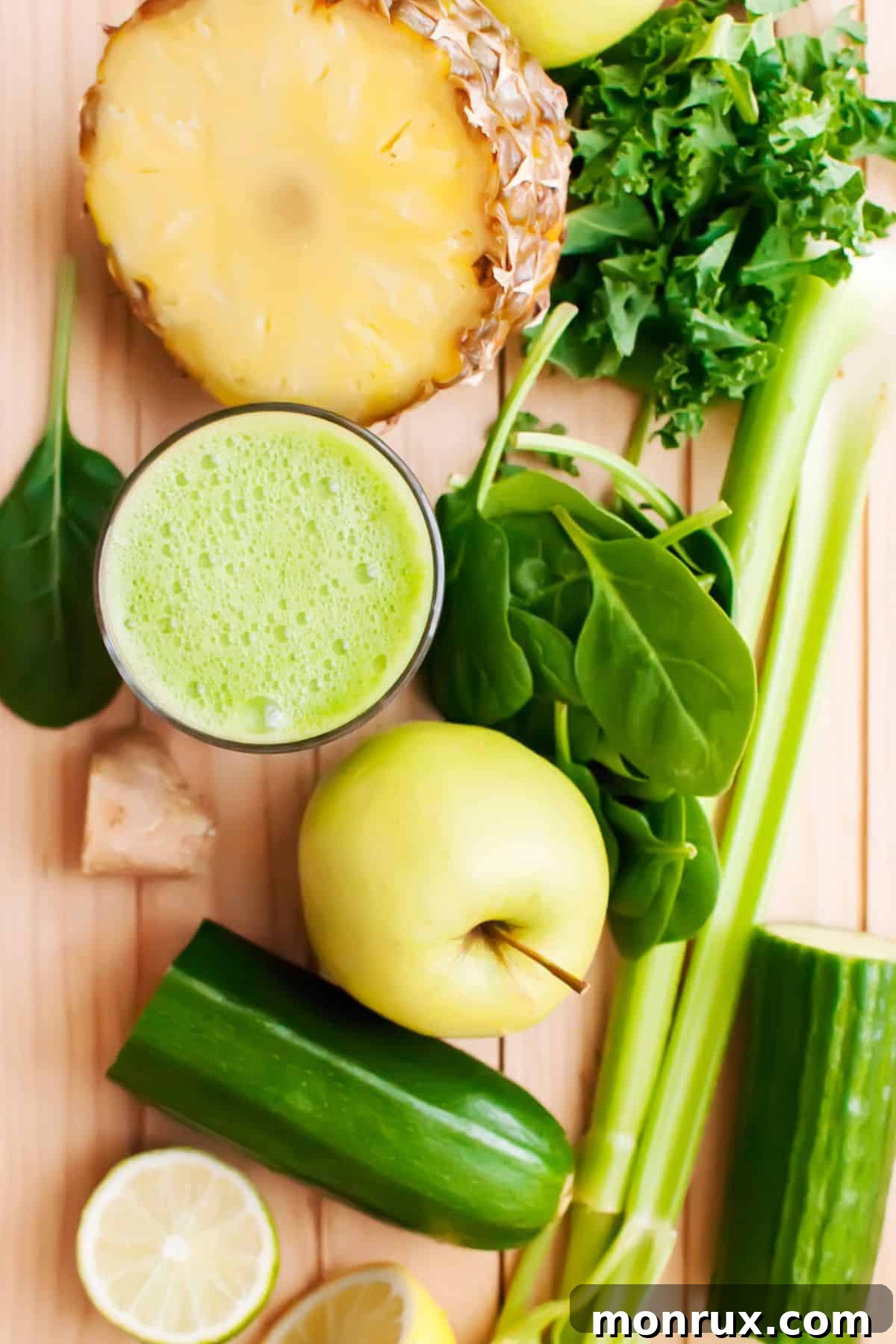 Overhead view of a glass of vibrant green anti-inflammatory juice, with fresh ingredients scattered around.