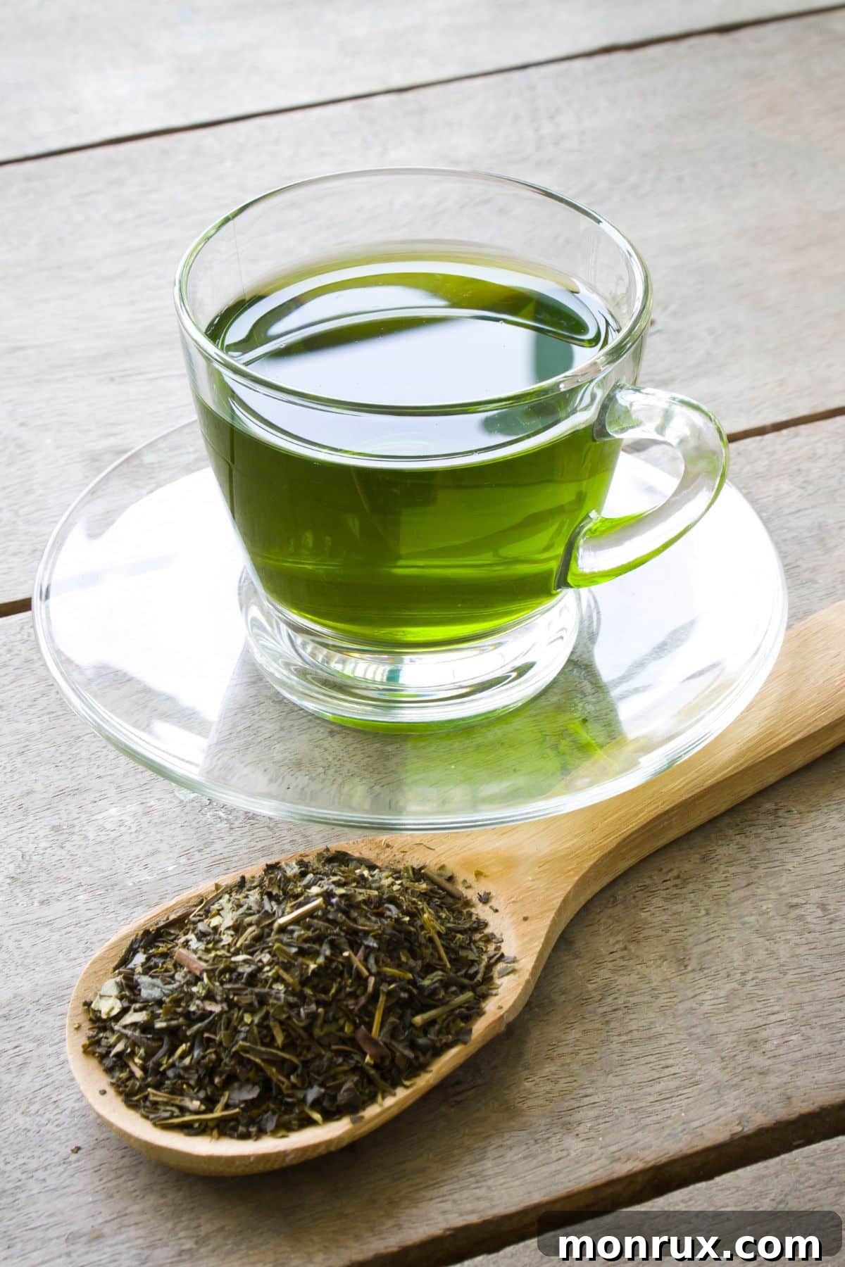 a cup of green tea next to a spoon of dried green tea.
