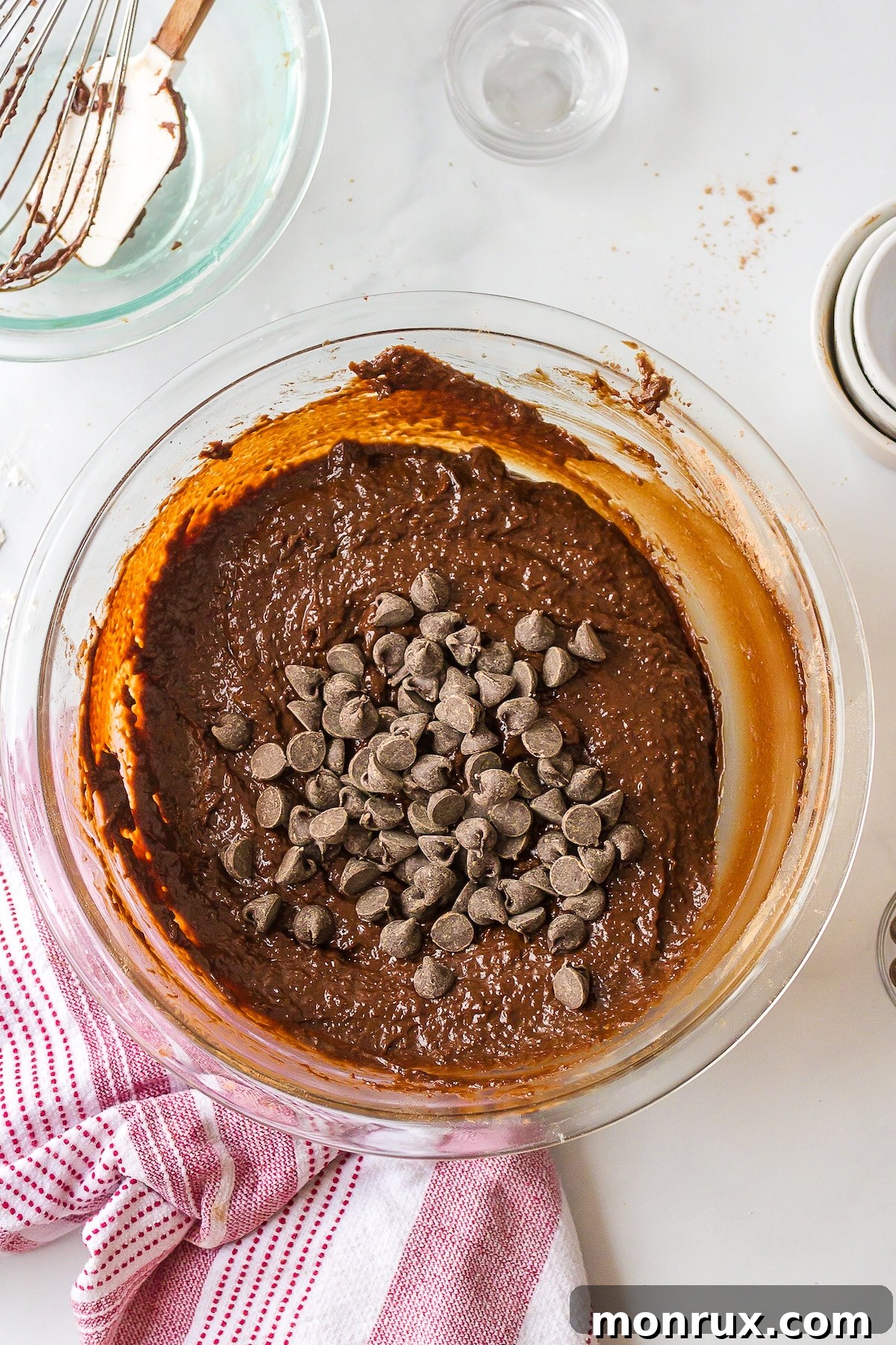 Thick, rich dairy-free brownie batter in a mixing bowl, folded with dark chocolate chips, ready to be poured into a baking dish.