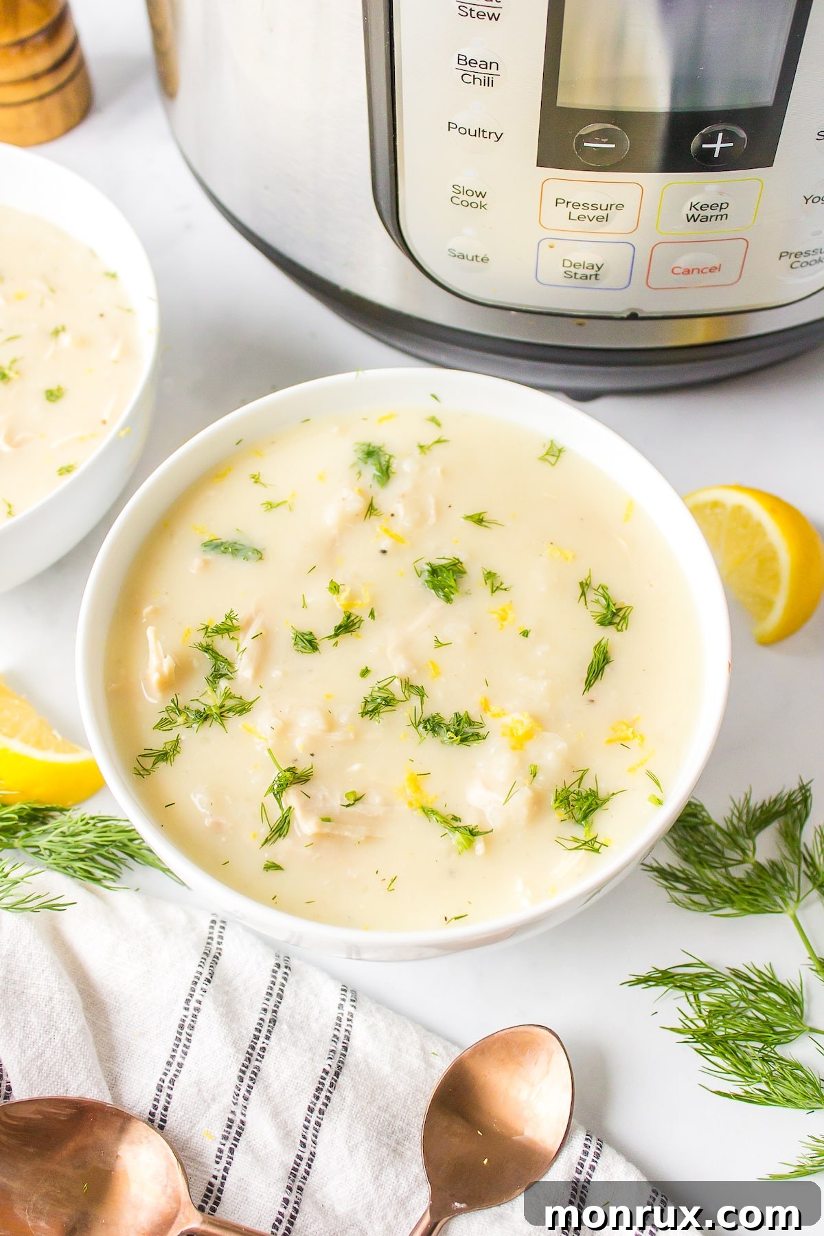 A vibrant bowl of Instant Pot Avgolemono soup, garnished with fresh dill.