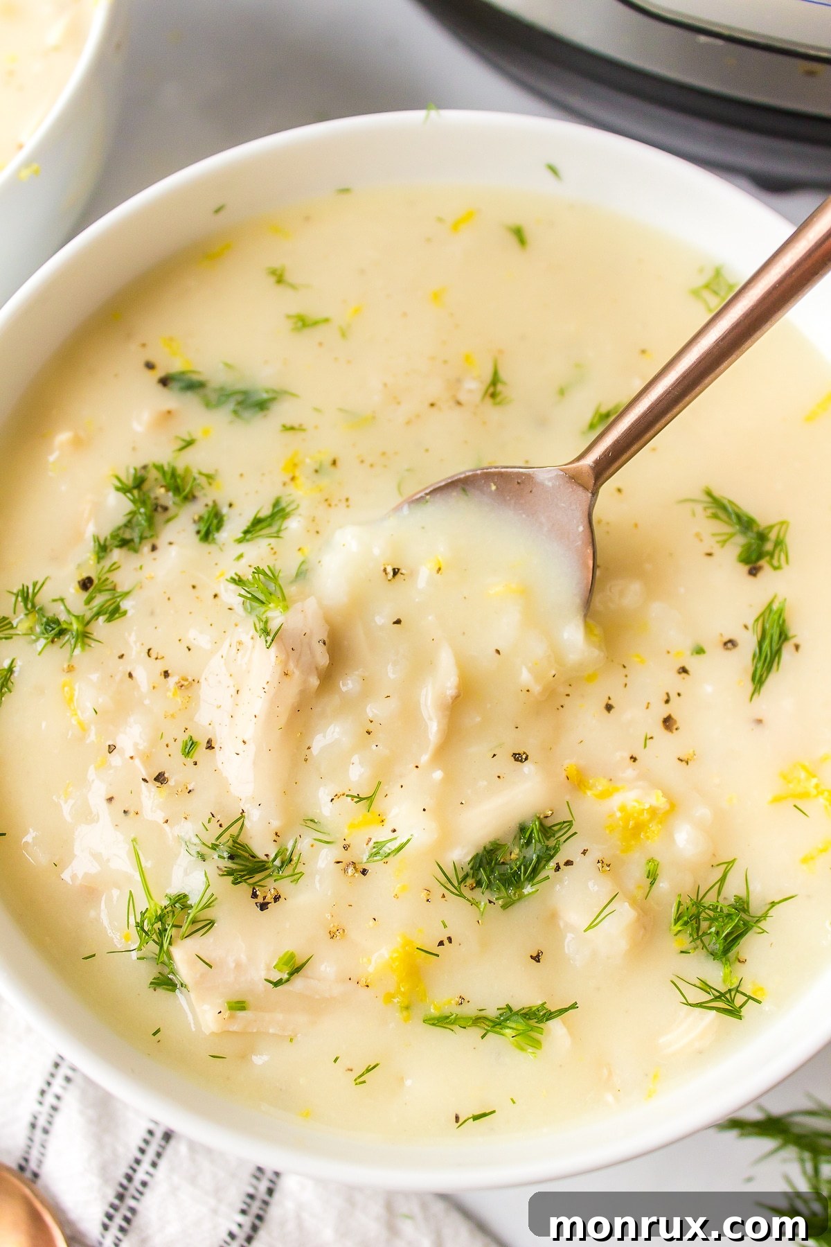 A spoon scooping creamy avgolemono soup from a bowl, highlighting its rich texture.