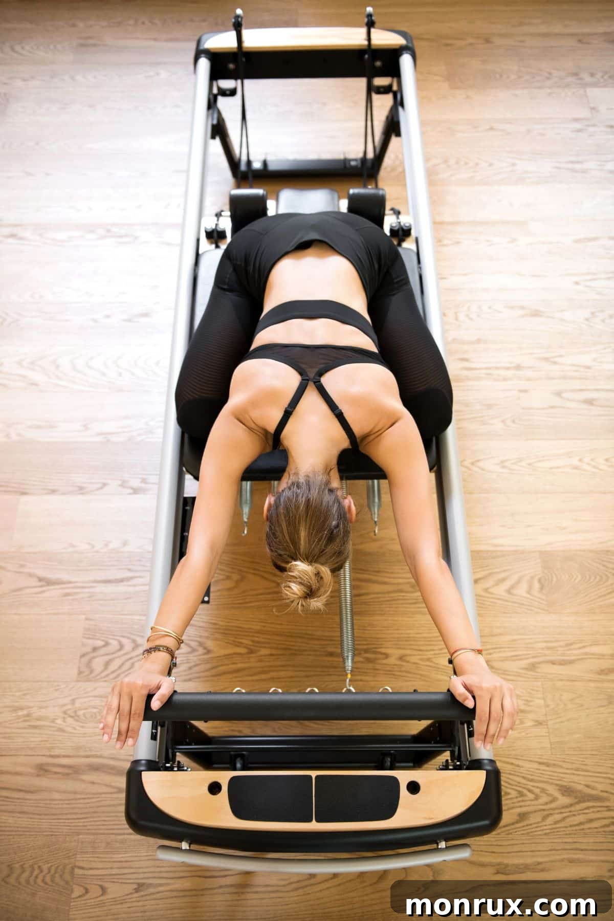 A woman performing an exercise on a Pilates Reformer, demonstrating core engagement and controlled movement.