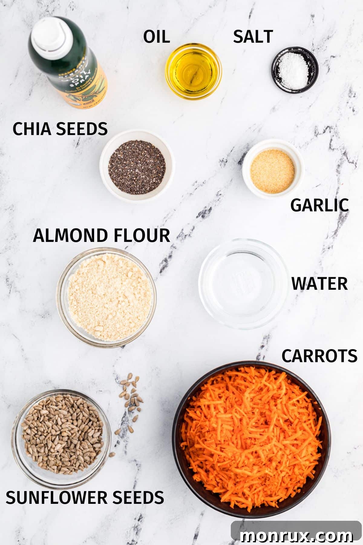 Individual ingredients for carrot crackers displayed in small white bowls on a light surface.