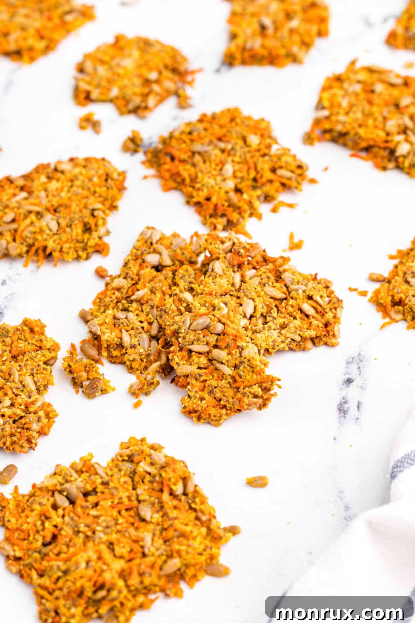 Freshly baked, crisp carrot pulp crackers arranged on a white surface, ready to be enjoyed.