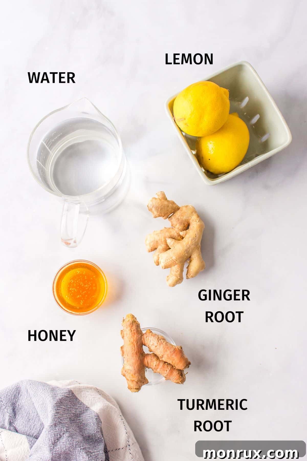 Fresh, vibrant ingredients for the tea including ginger root, turmeric root, and bright yellow lemons, neatly arranged.