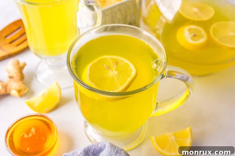 A beautifully composed shot of golden lemon ginger turmeric tea in a white ceramic mug, signifying warmth and health.