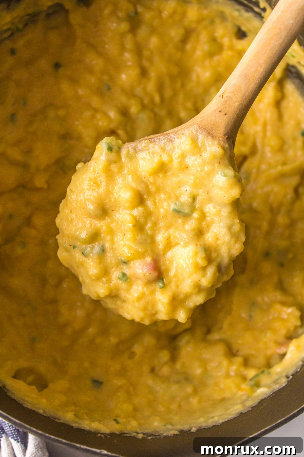 A wooden spoon scooping up a portion of Mexican mashed potatoes from a bowl.
