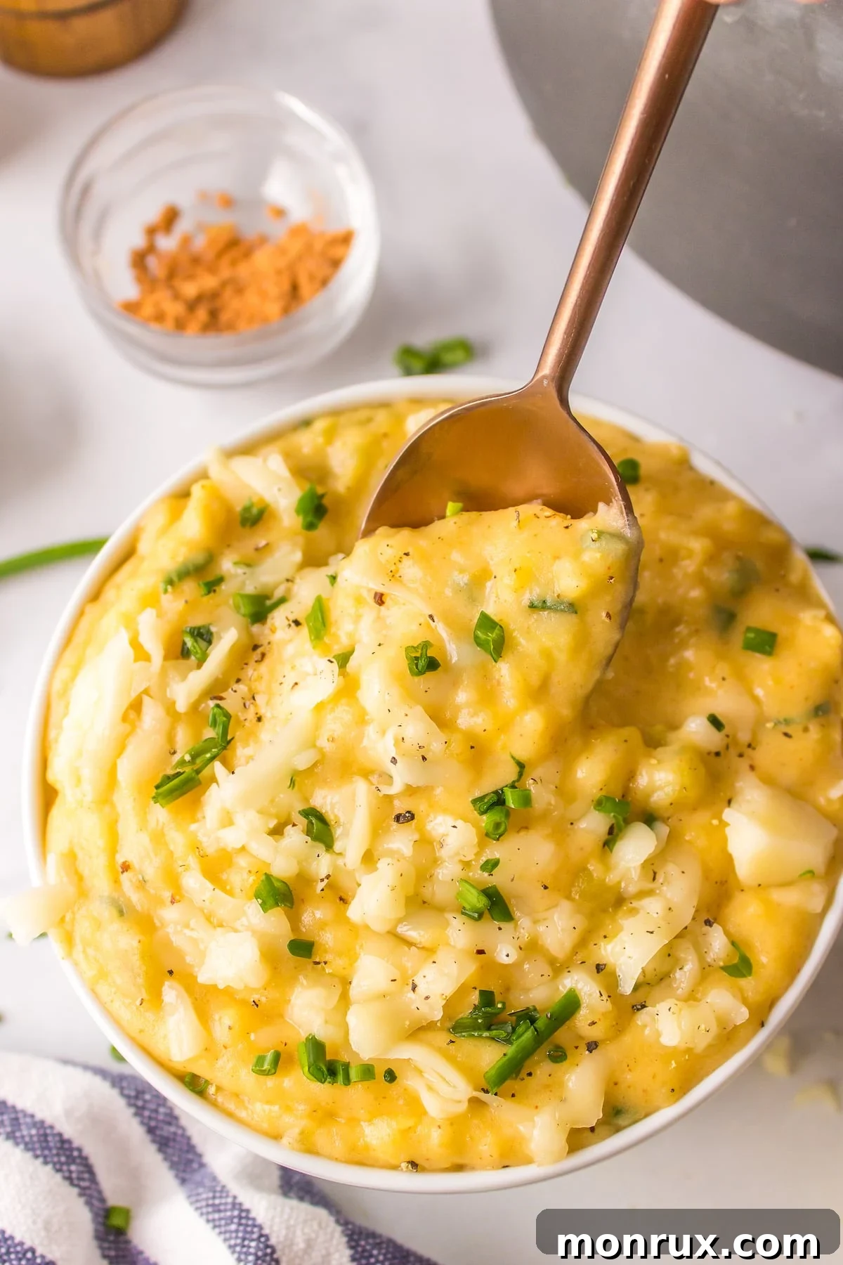 A spoon dipping into a bowl of creamy Mexican mashed potatoes, showing the texture.