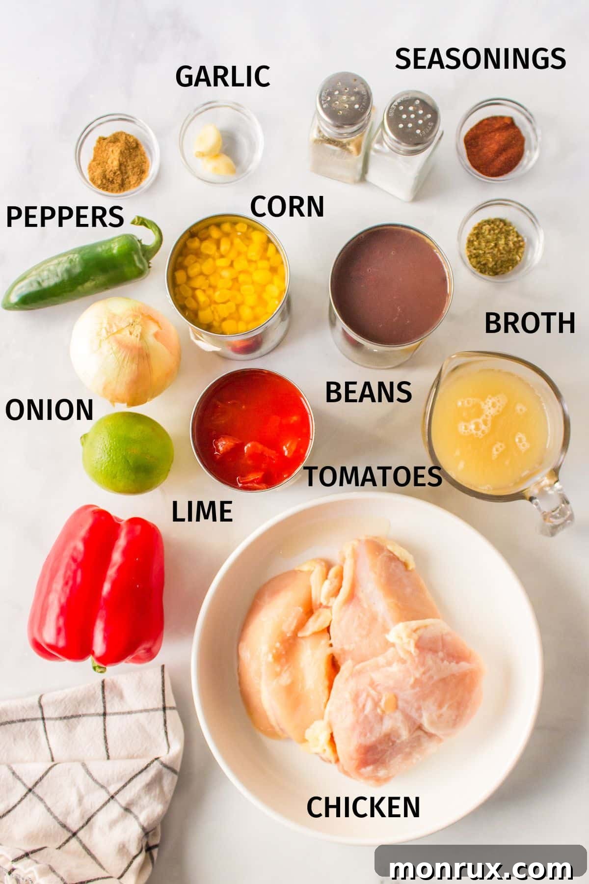 Fresh ingredients laid out for Panera chicken tortilla soup preparation: chicken breasts, red bell pepper, jalapeños, corn, black beans, canned tomatoes, and spices.