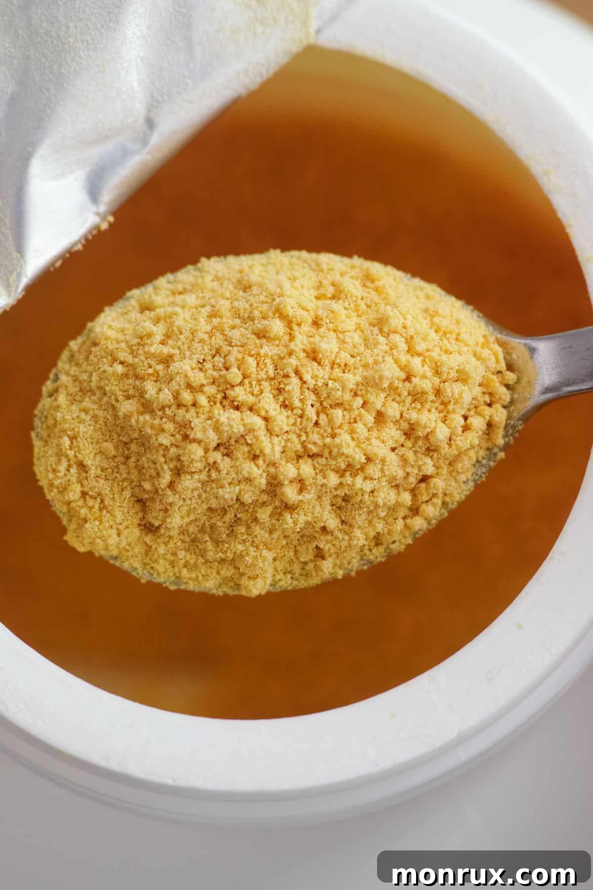 A spoon full of soy lecithin coming out of a jar.