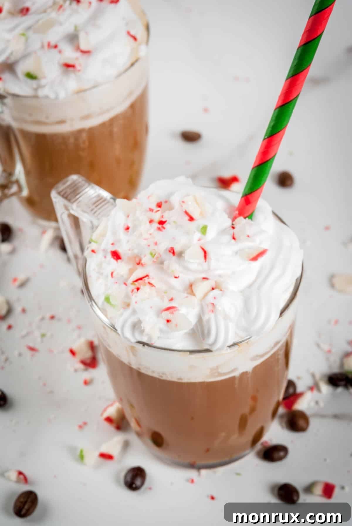 Two steaming cups of homemade peppermint coffee, garnished with whipped cream and crushed candy canes, set against a festive holiday backdrop.