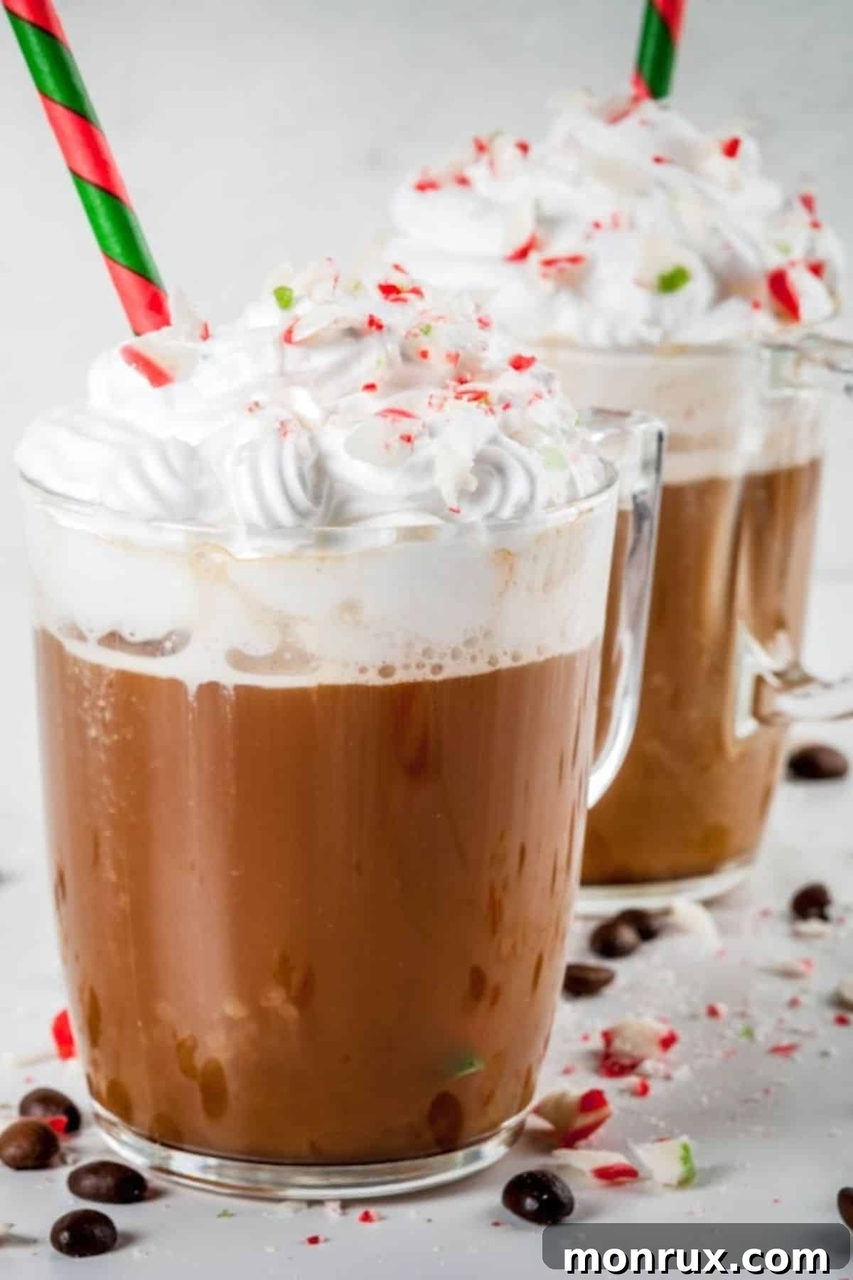 A tall glass of iced peppermint coffee, topped with a generous swirl of whipped cream and garnished with chocolate shavings.