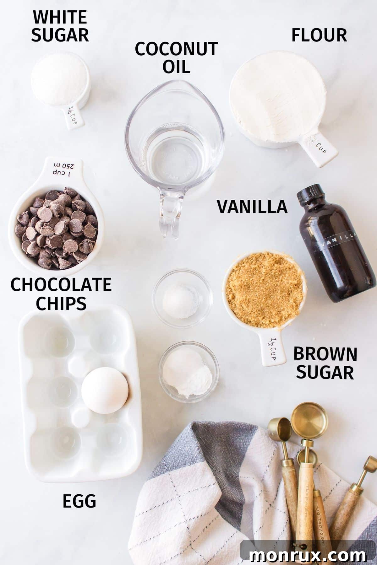 All the essential ingredients for making butterless chocolate chip cookies laid out on a clean white countertop.