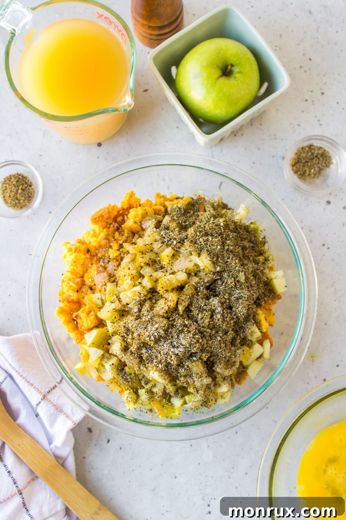A large mixing bowl containing crumbled cornbread, sautéed vegetables, and herbs for the stuffing mixture.