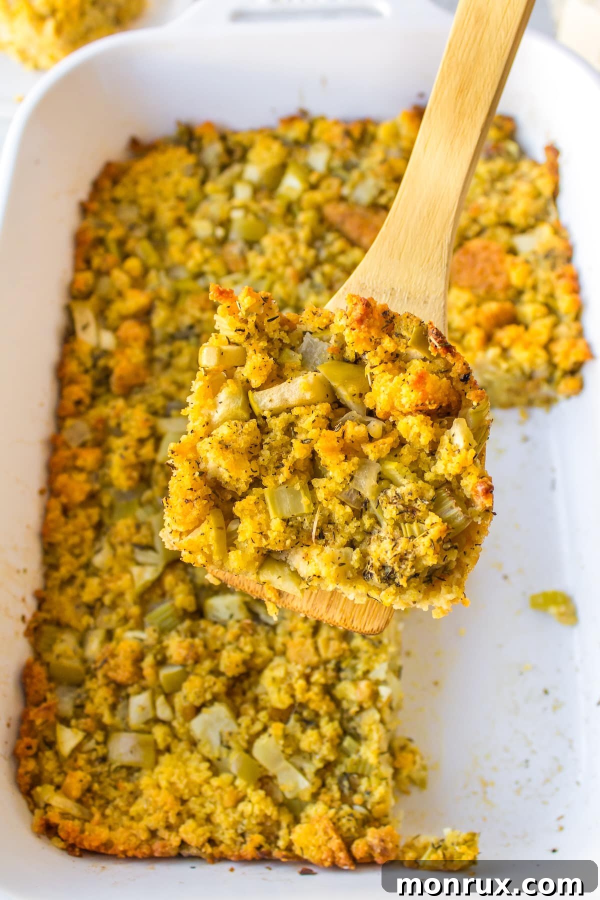 A generous serving of gluten-free cornbread stuffing being lifted with a spatula, showcasing its texture.